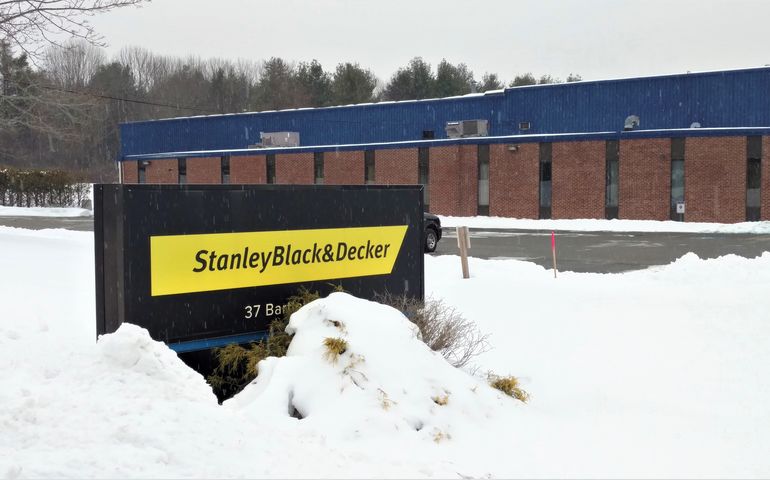outdoor sign, surrounded by snow, in front of one-story industrial building
