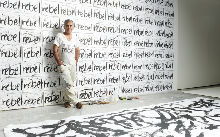 Artist standing in front of wall art 