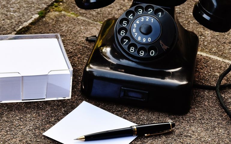 Rotary phone with pen and paper on a desk 