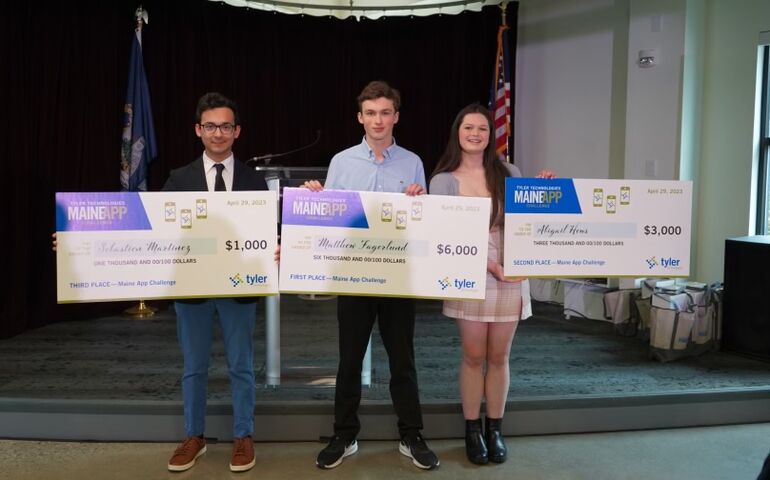 Three winners on stage with oversized checks 