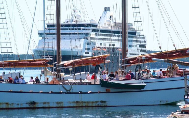 cruise ship behind big schooner on the water with people
