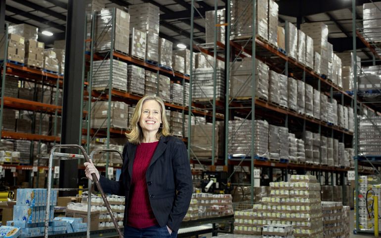 Kristin Miale at Good Shepherd Food Bank HQ in front of food supplies