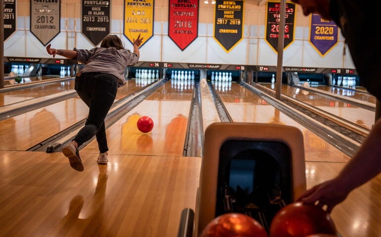 person throwing a bowling ball down a lane