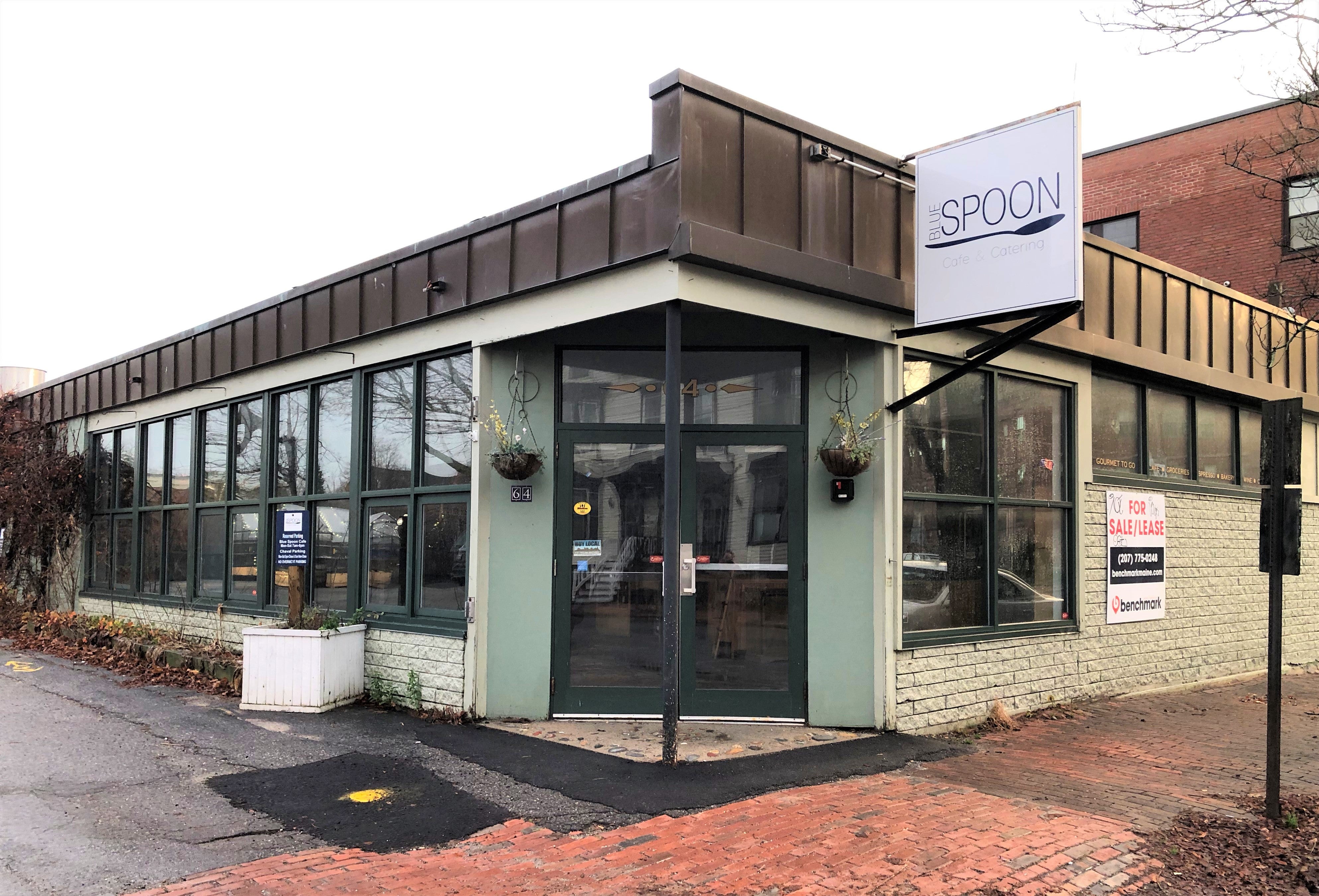 a one story green brick building with a door on the corner and a sign that says spoon