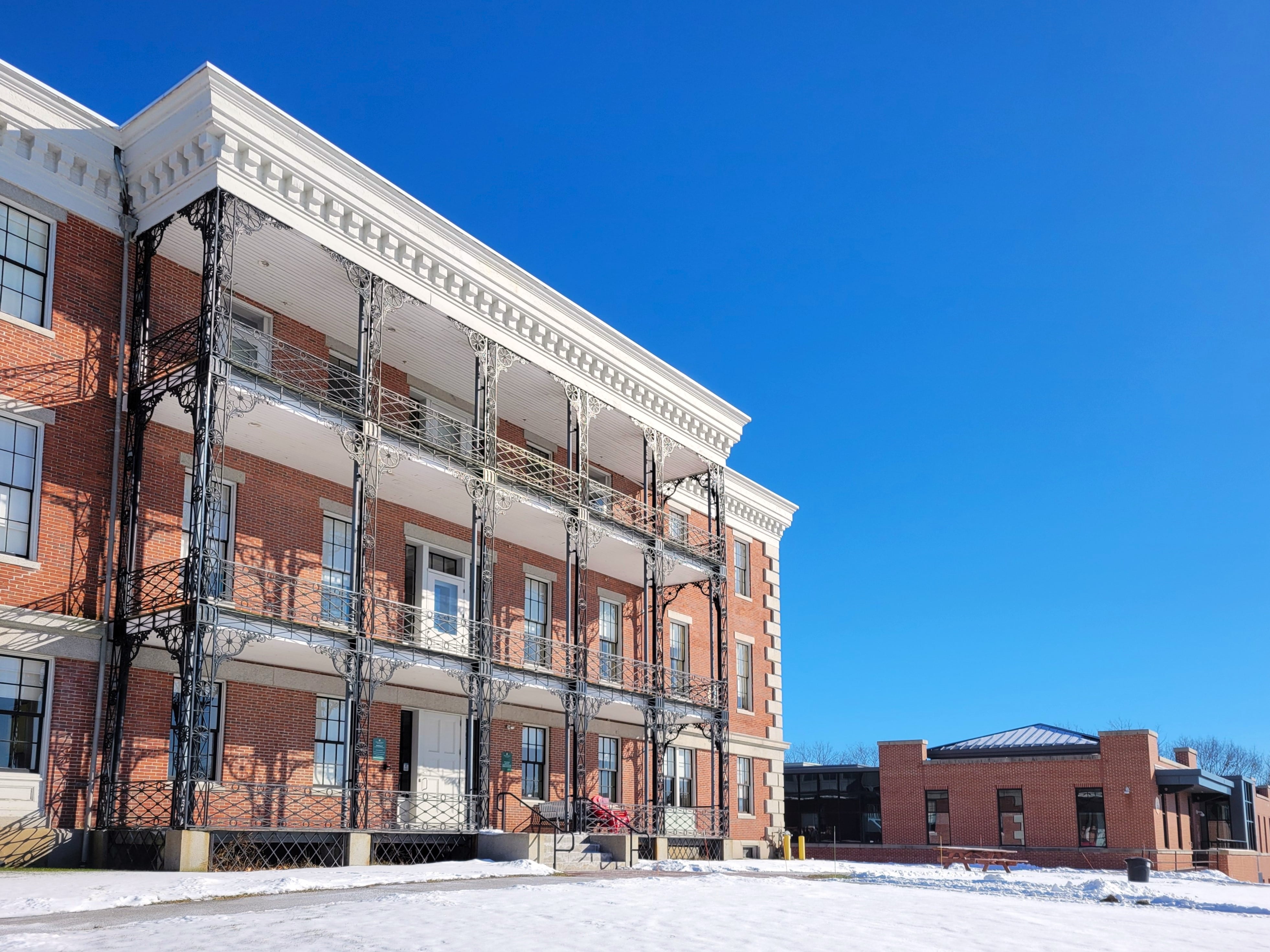 an ornate three-story brick building next to a modern one-story brick building