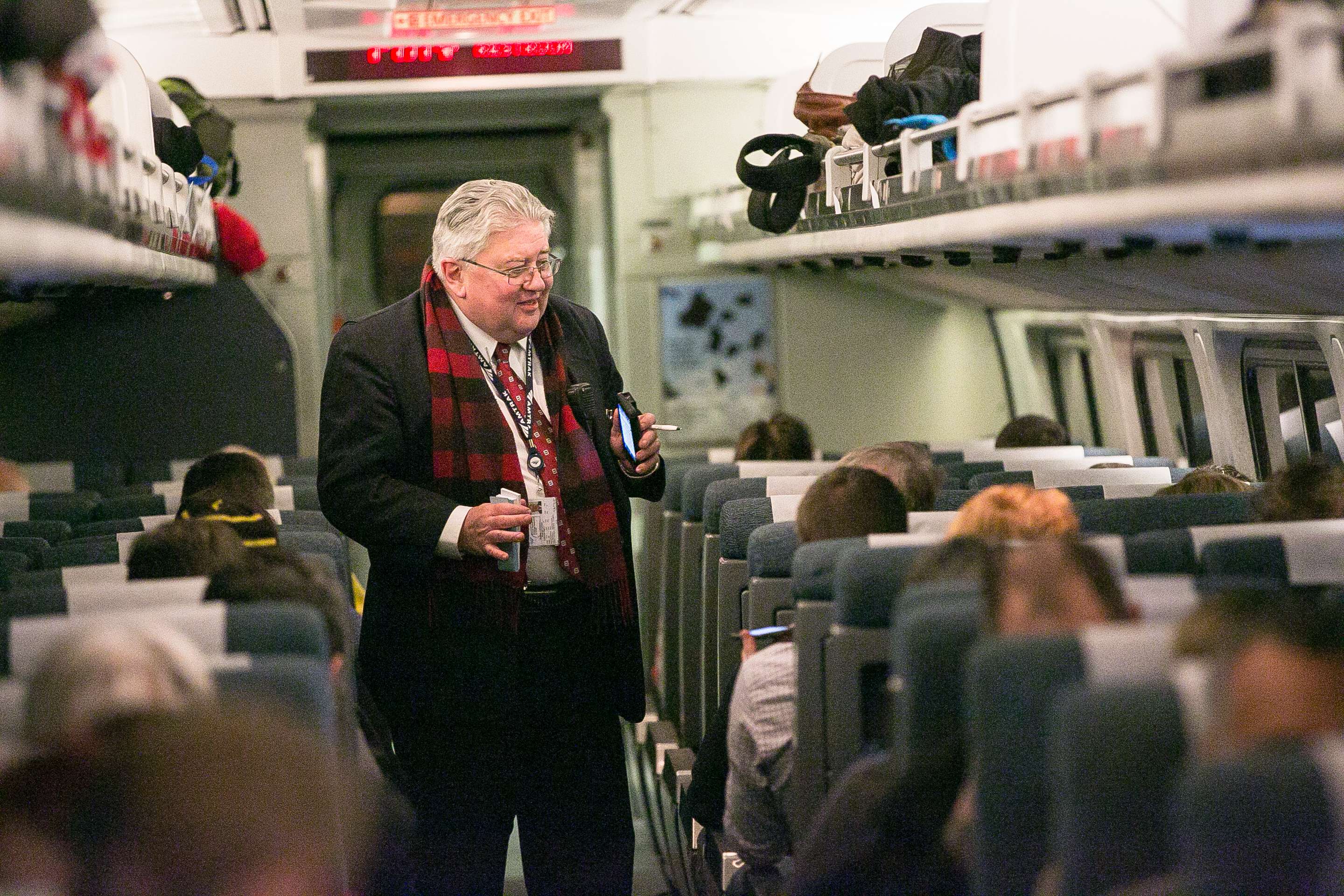 Conductor taking tickets inside am Amtrak Downeaster train