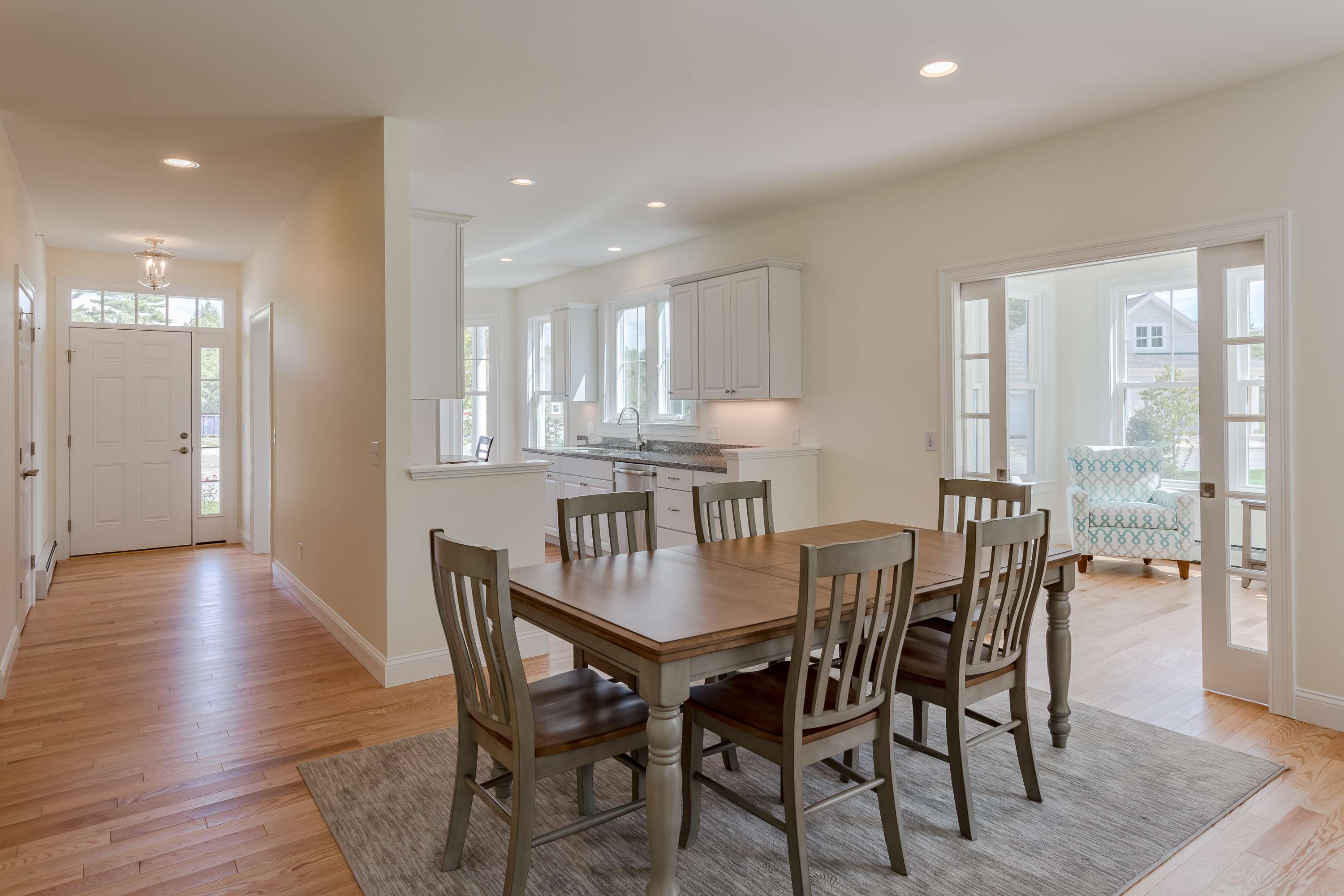 The interior of a new home with wood floors, a small kitchen and a sunroom to the right