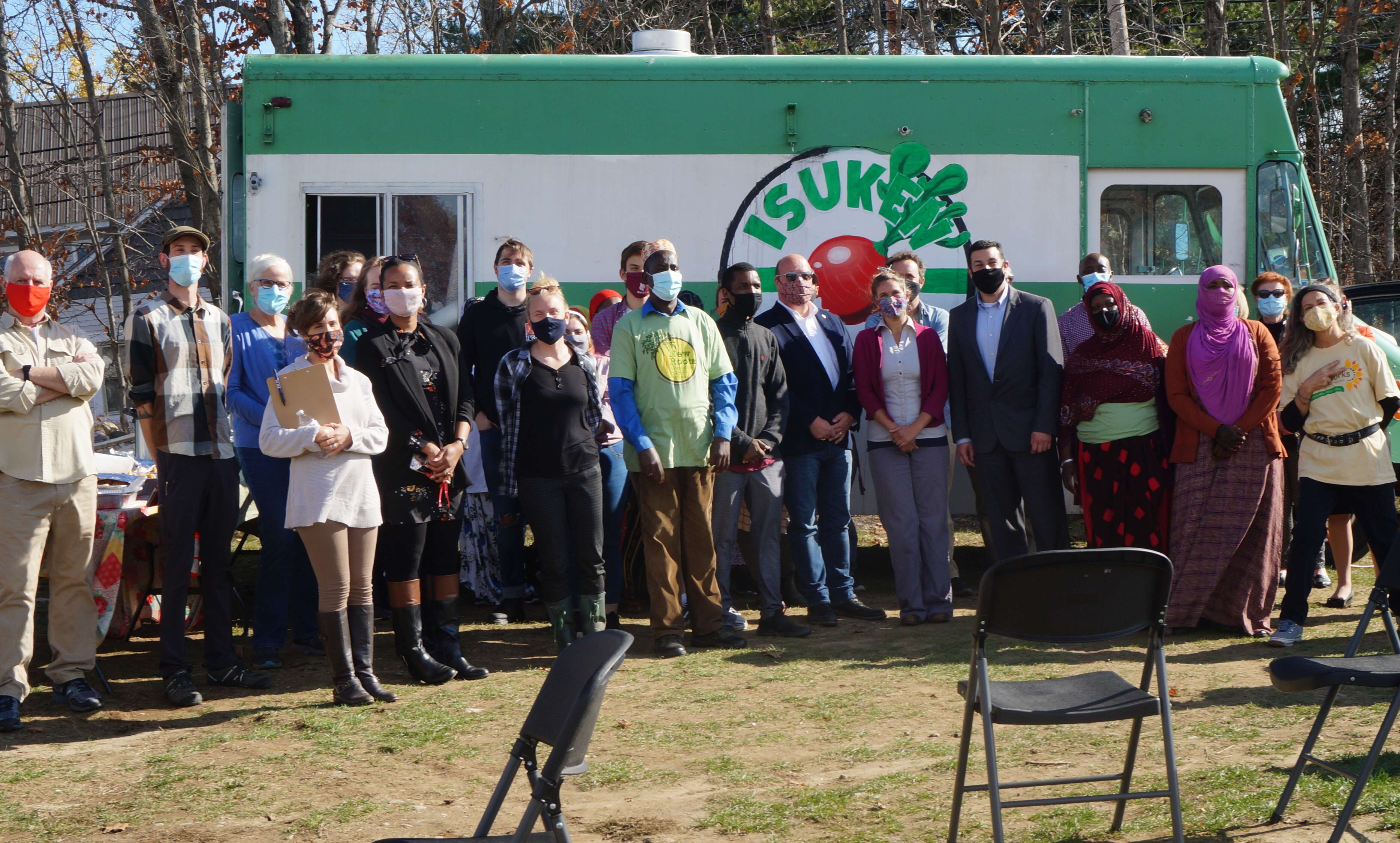a large diverse group of people standing in front of a food truck that says Isuken Cooperative