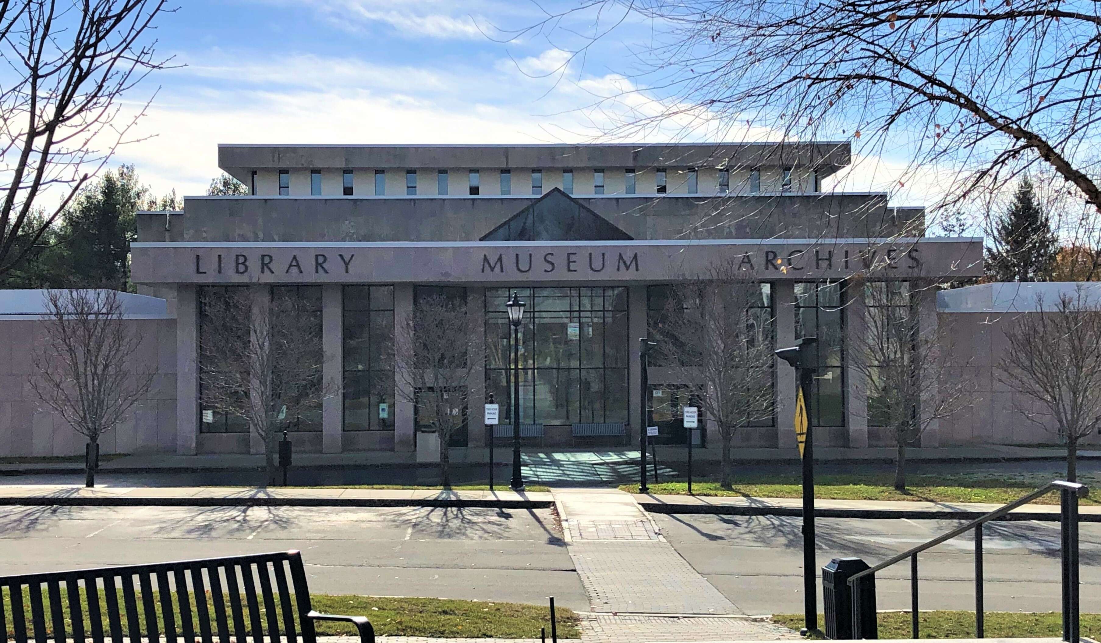 a low concrete building with big windows and a letters above the entrance that say Maine state library museum archives