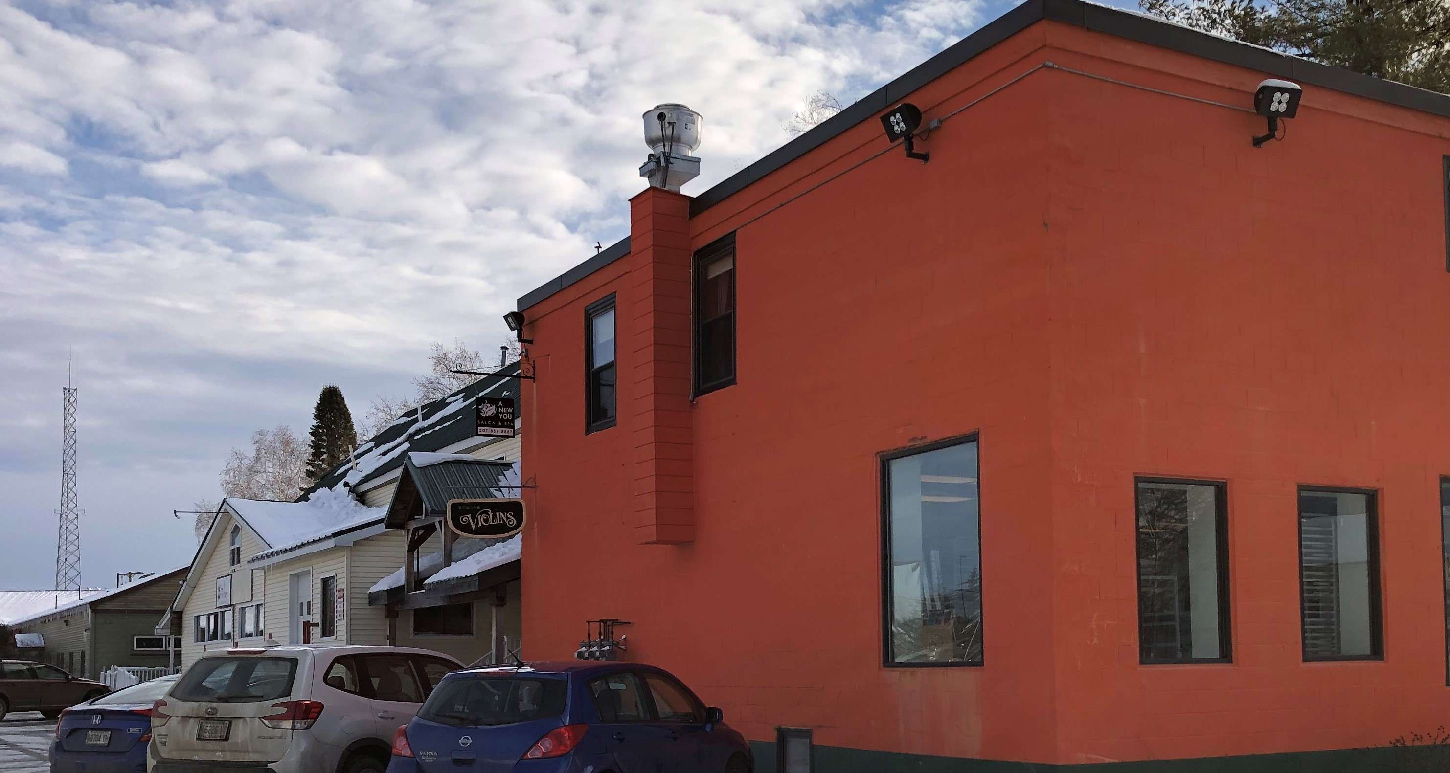 a long row of connected buildings with a large two story orange one at the front and a variety of styles and different colors behind it