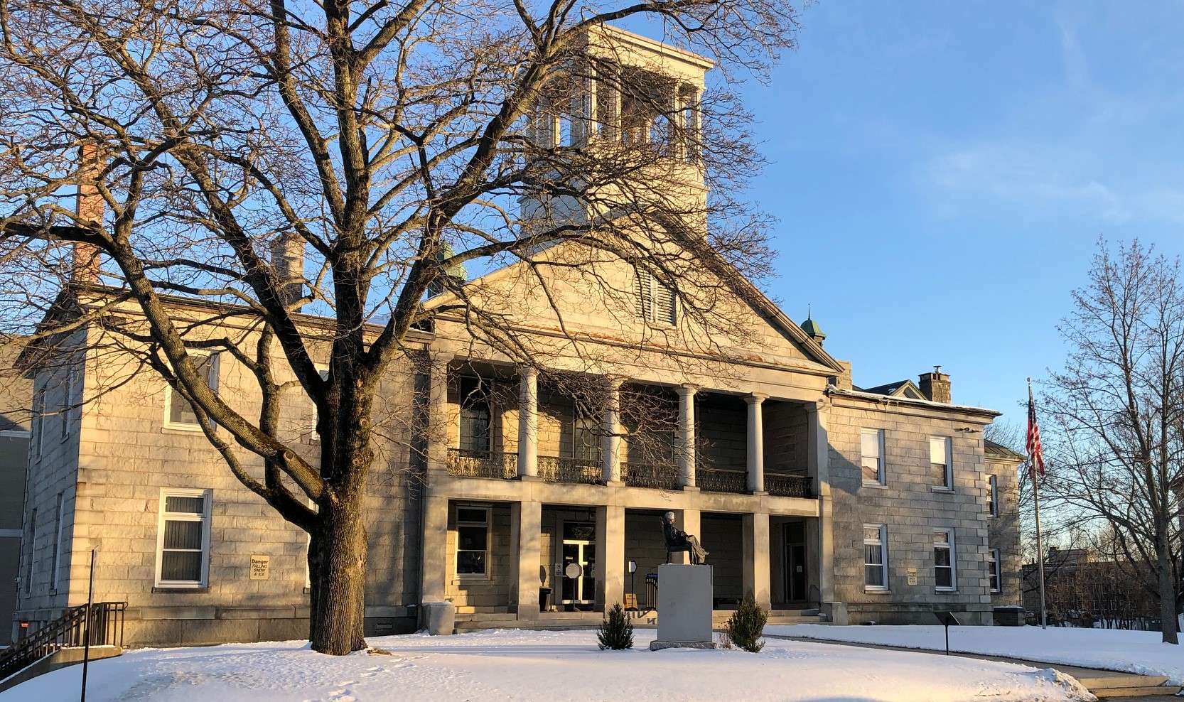 A 200-year-old granite palladian building with a small statue on a granite column in front