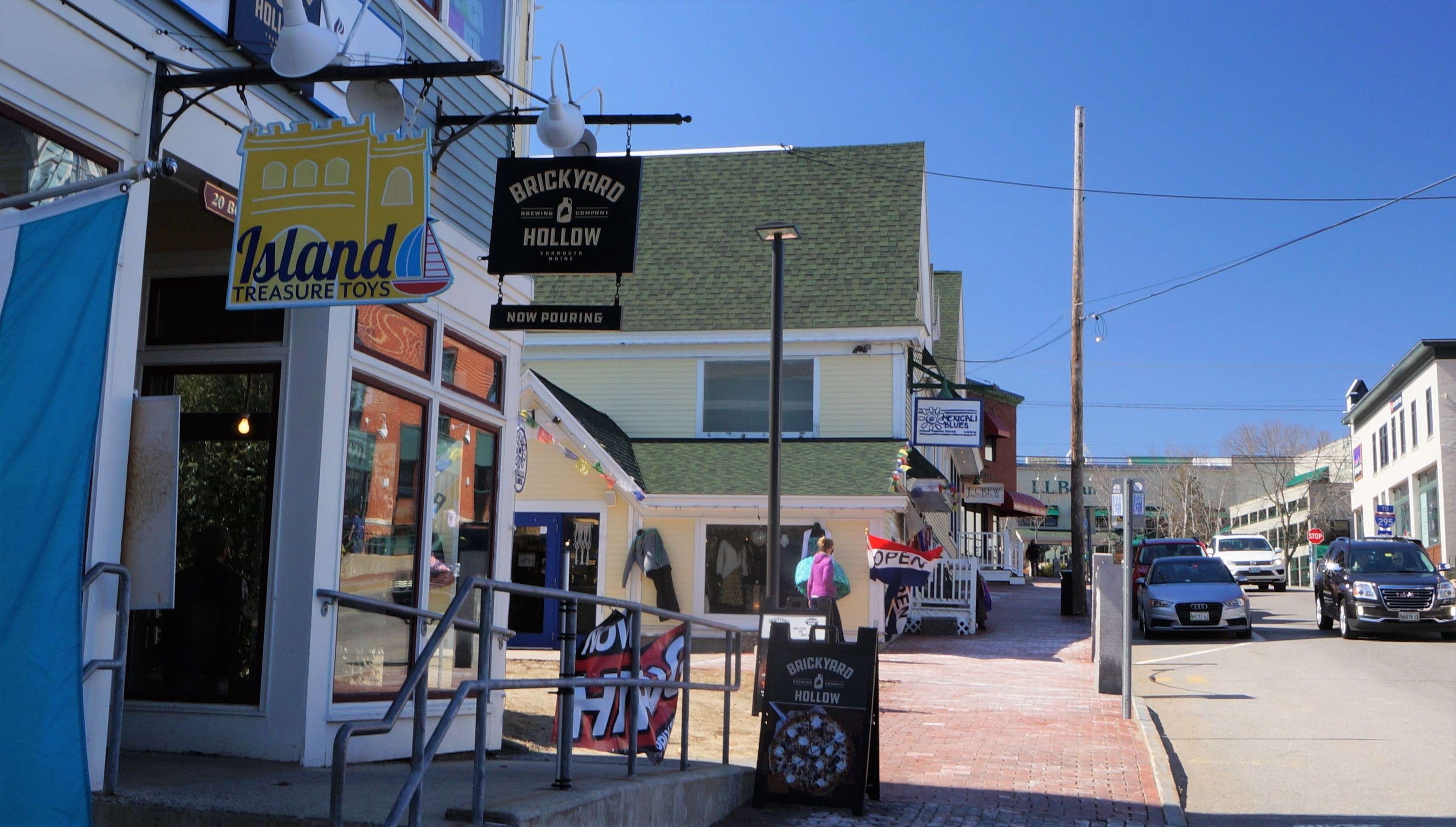 a storefront on a street full of small colorful storefronts has a sign that says Brickyard Hollow