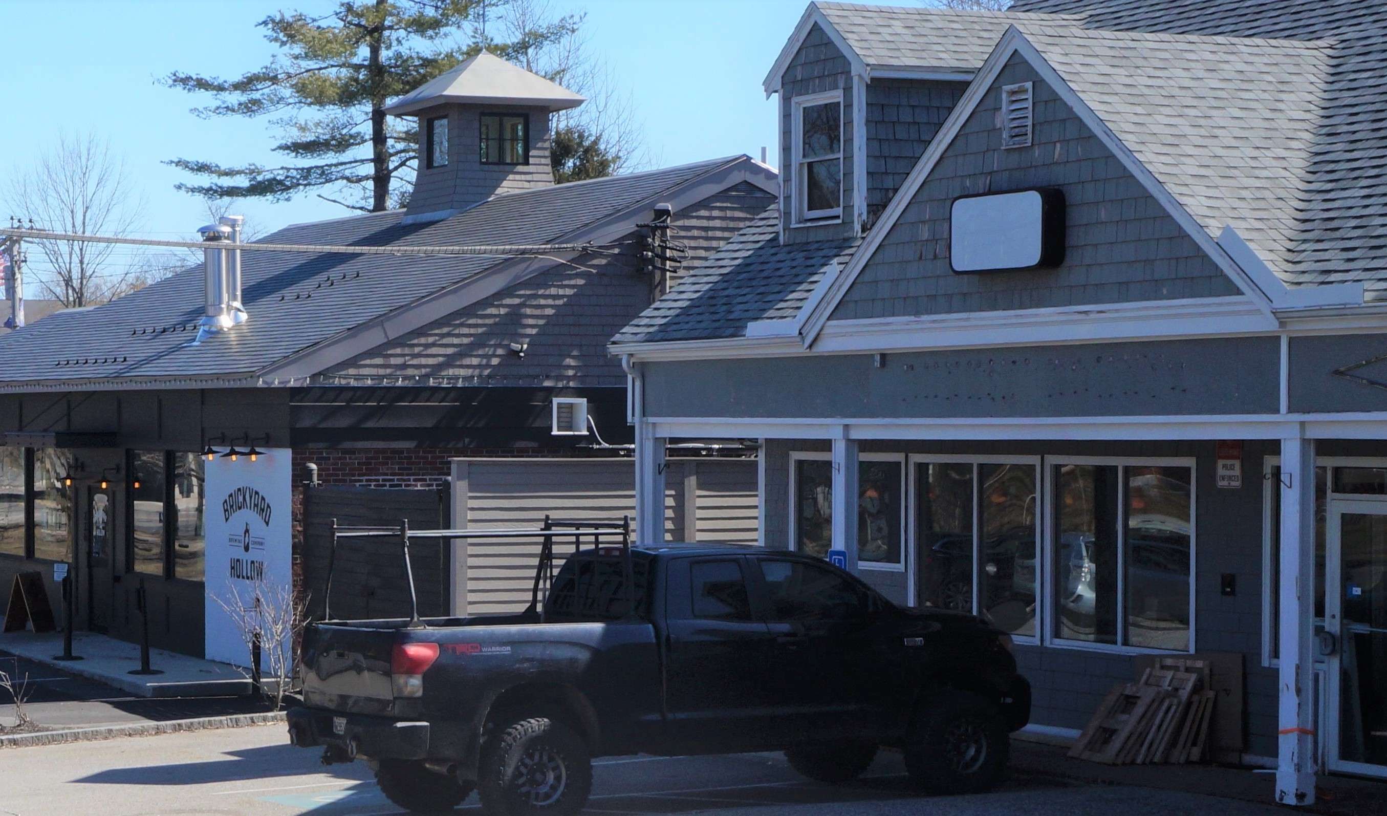 a small commercial building with a truck parked in front and no sign next to another building that says brickyard hollow