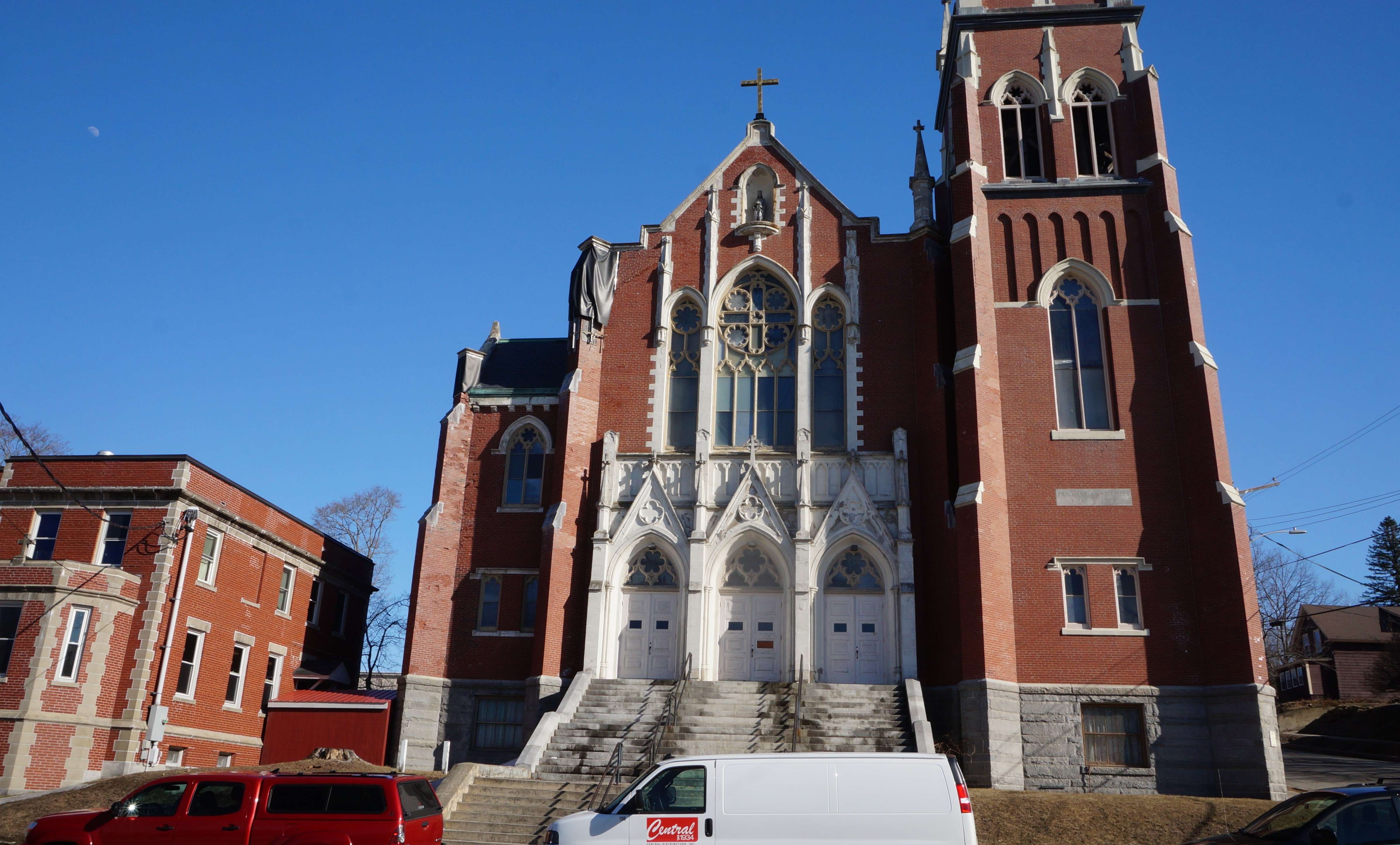 a large old brick church with granite steps leading up to three white doors with peeling paint