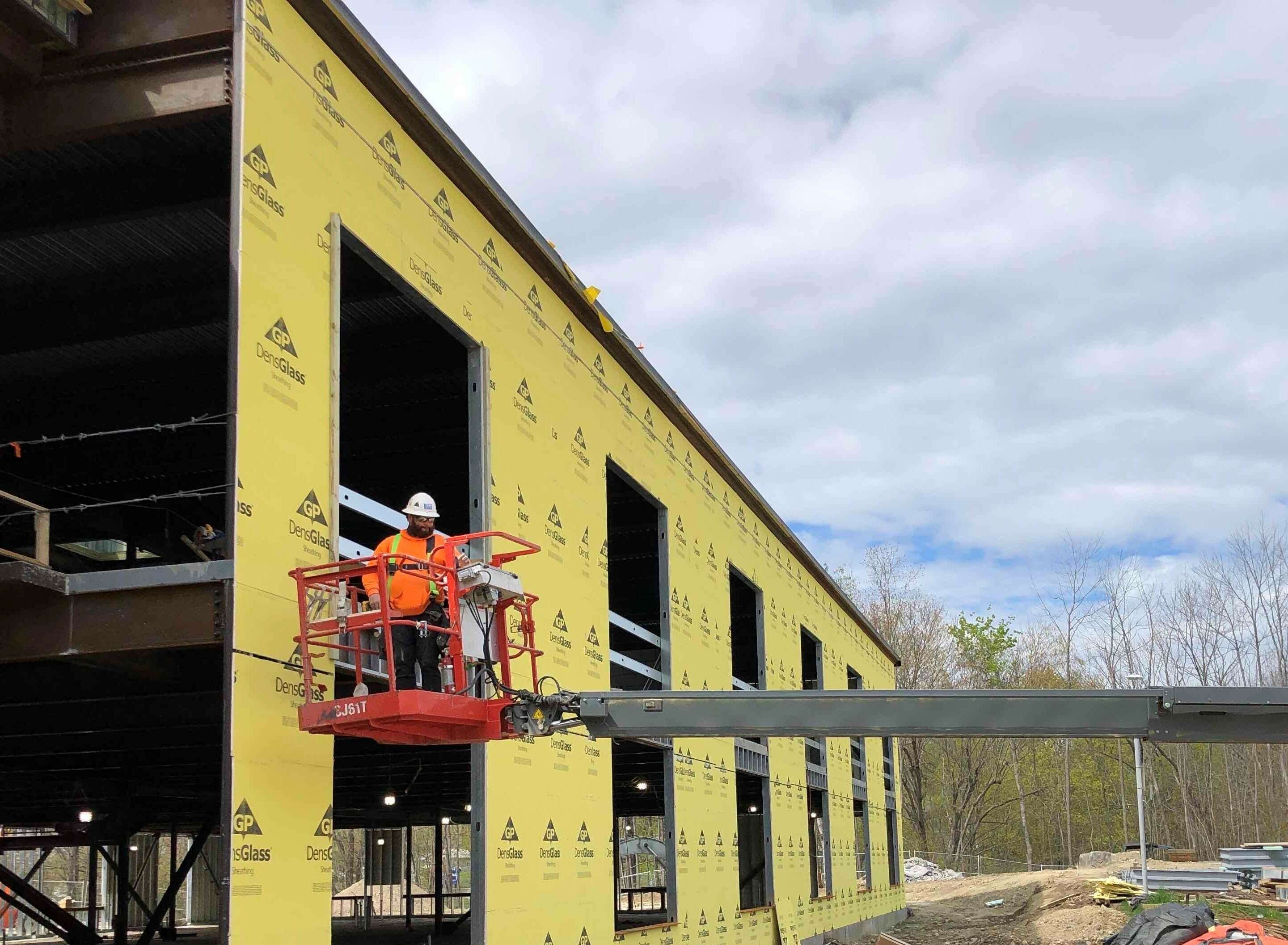 An under construction two story building with a man in a cherry picker