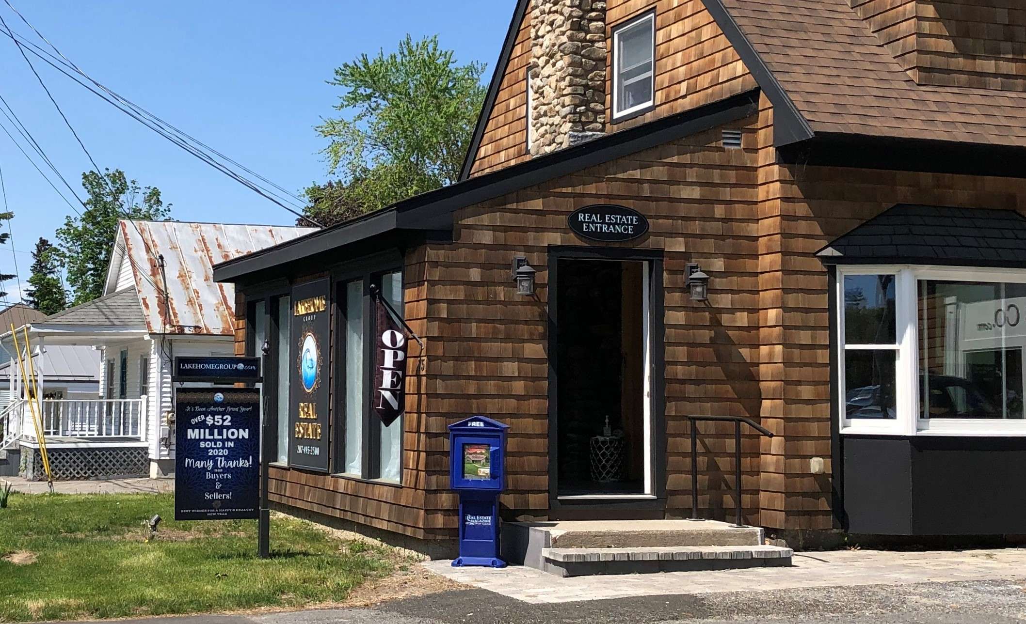A cedar shingled house with a sign that says lakehome group $52 million sold in 2020 many thanks buyers and sellers