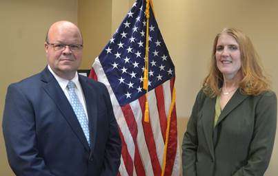 Two people standing by a flag