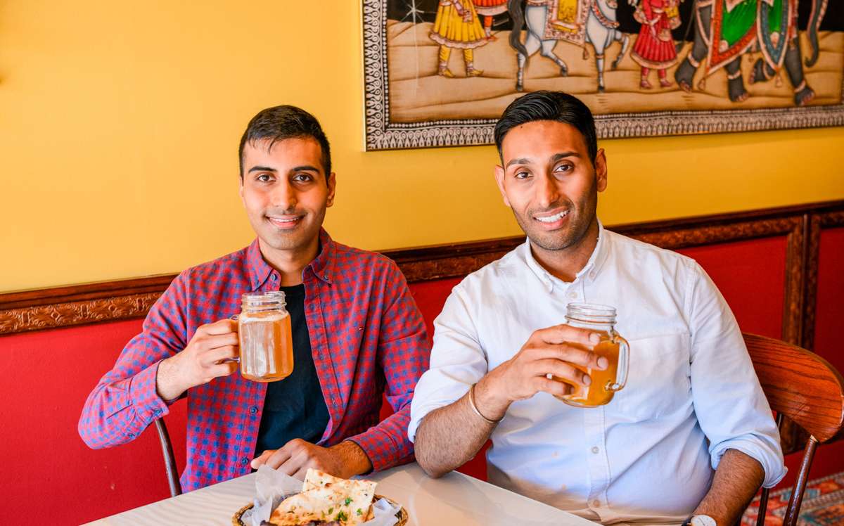 Van and Sumit Sharma at Indian restaurant holding up glasses with beer 