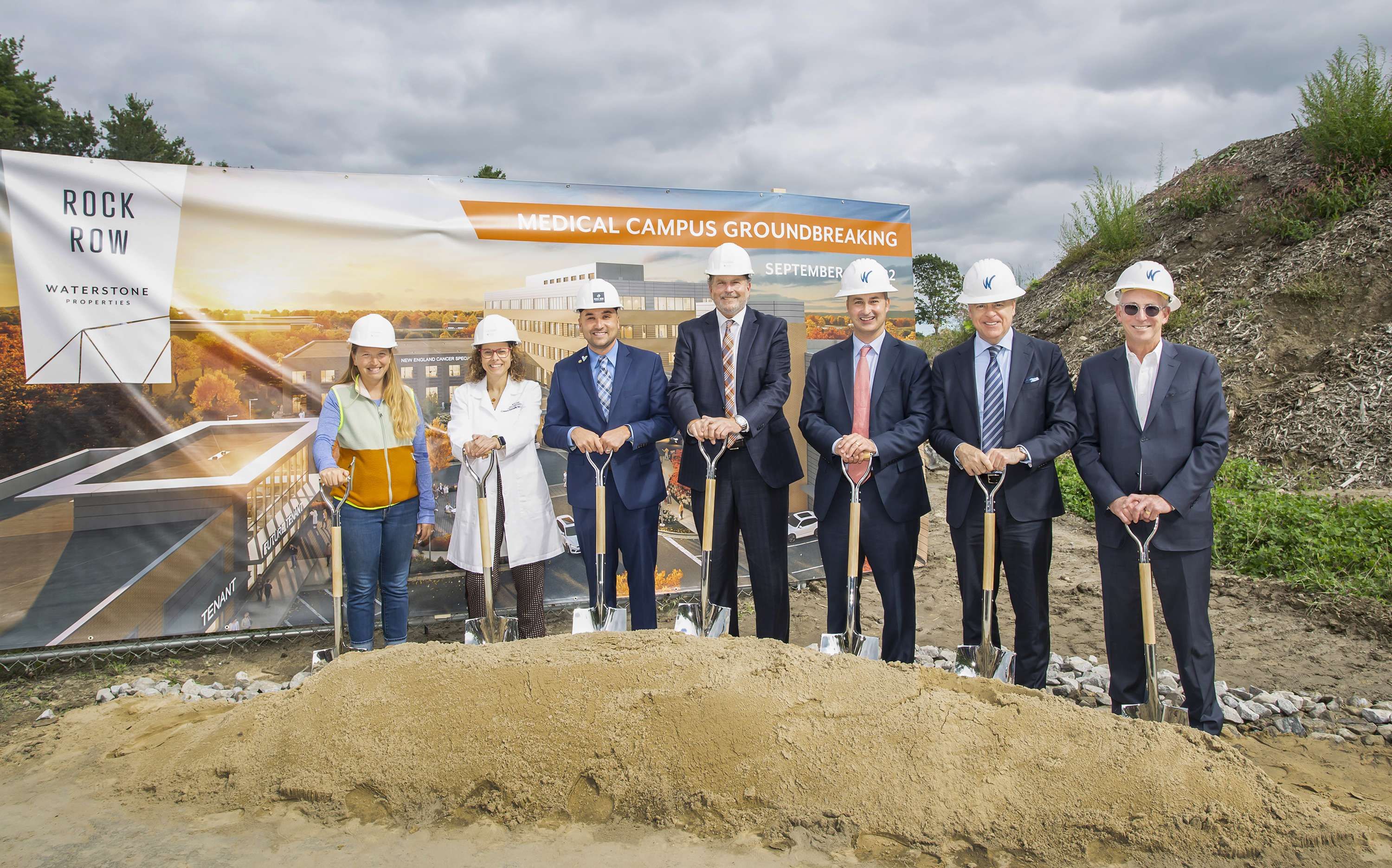 people posing with shovels and sand pile