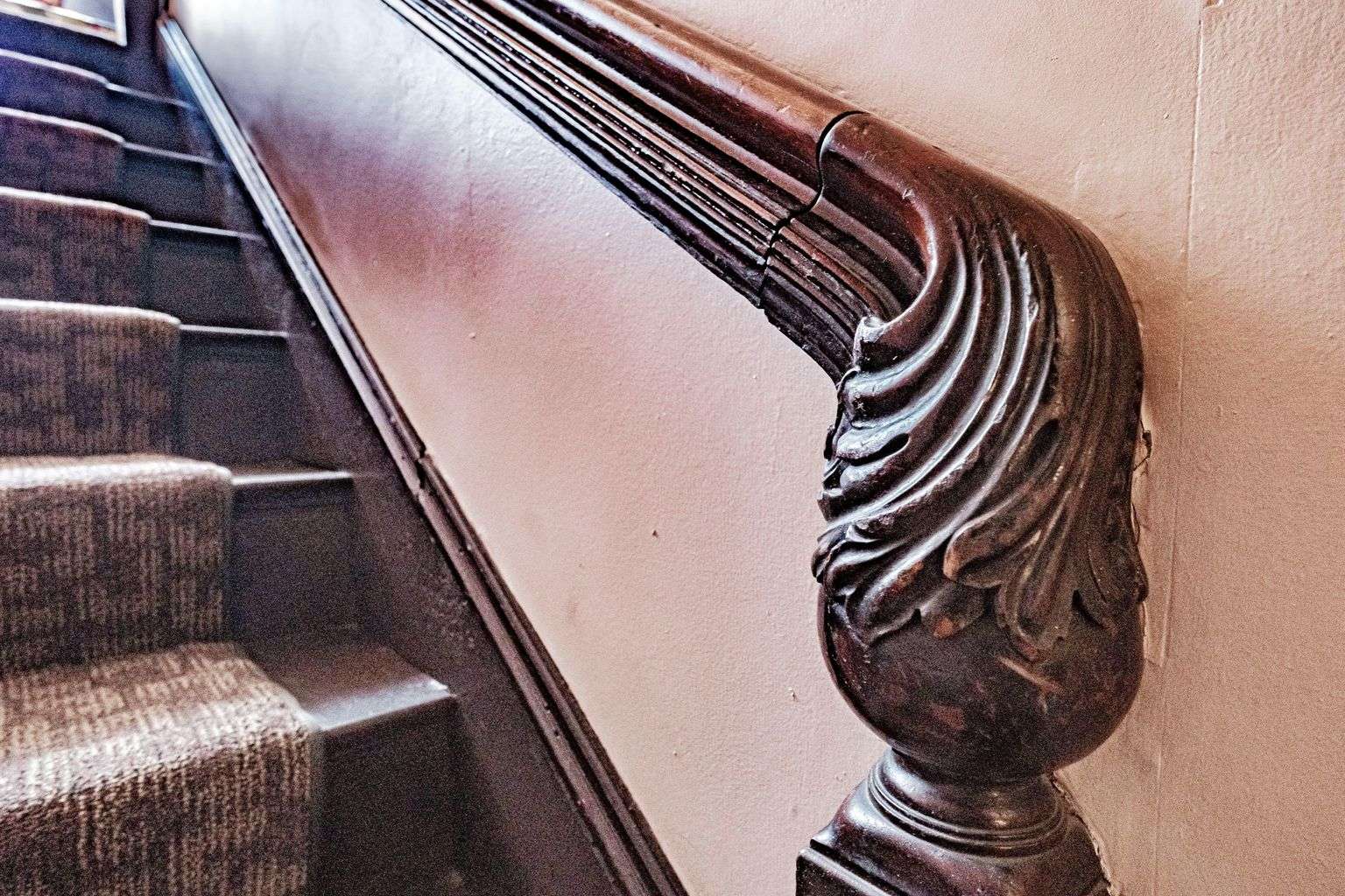 old wood bannister and carpeted stairs