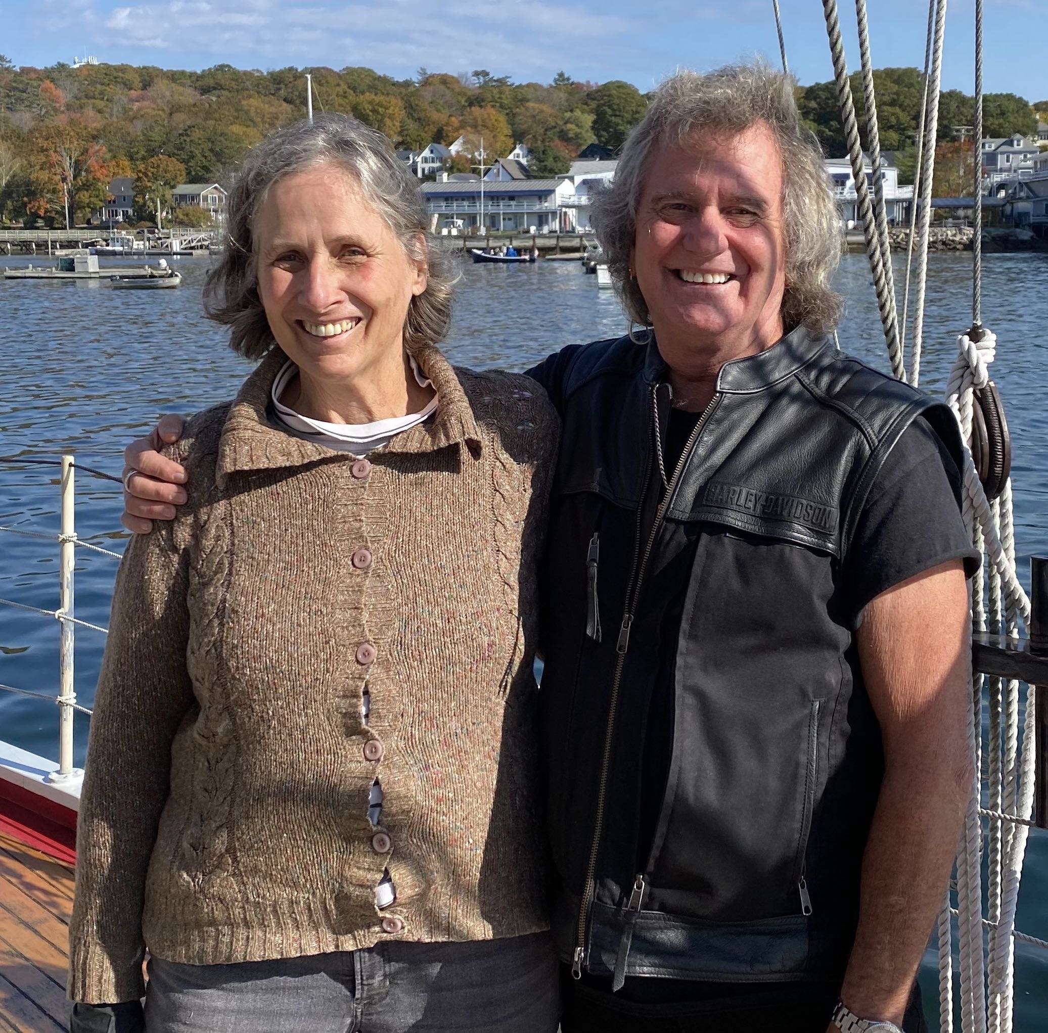 2 people embracing and smiling by harbor