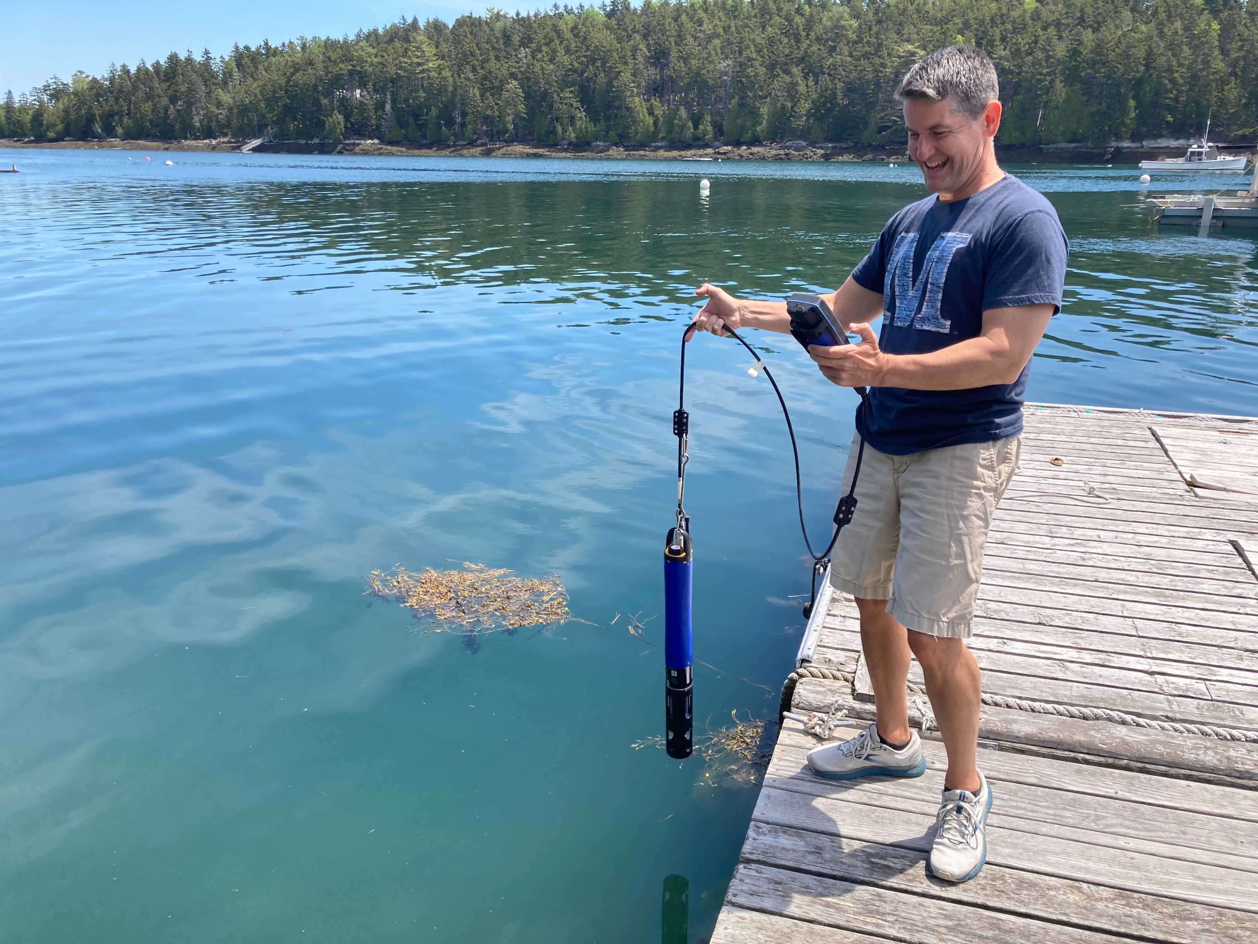 person on dock dangling equipment over water