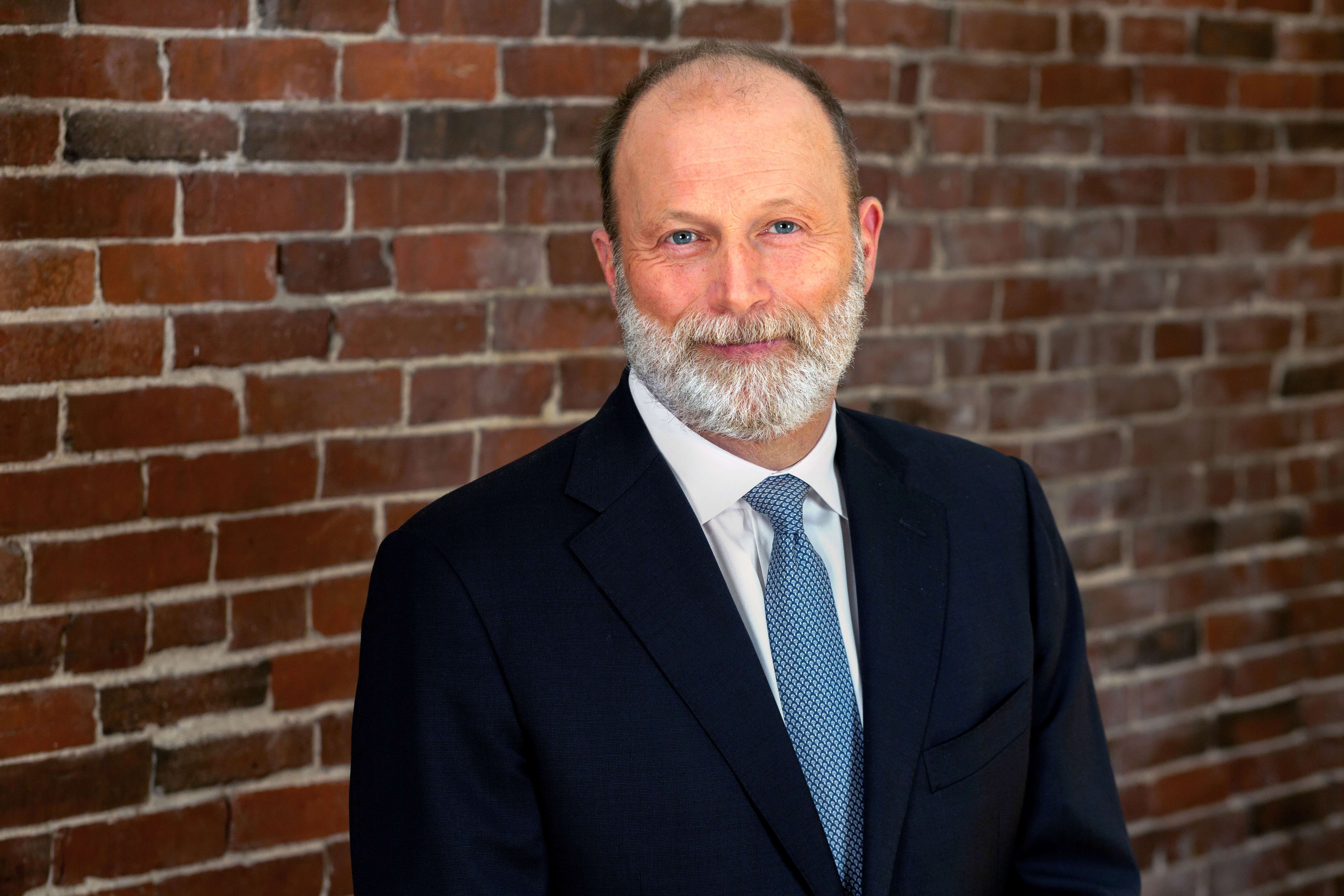 person in suit and tie in front of brick wall