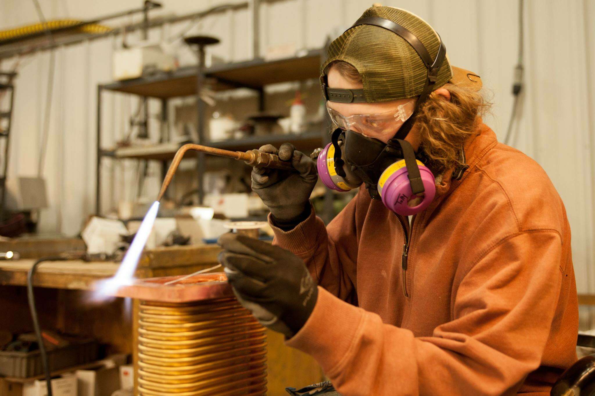 person in orange suit and goggles with machinery