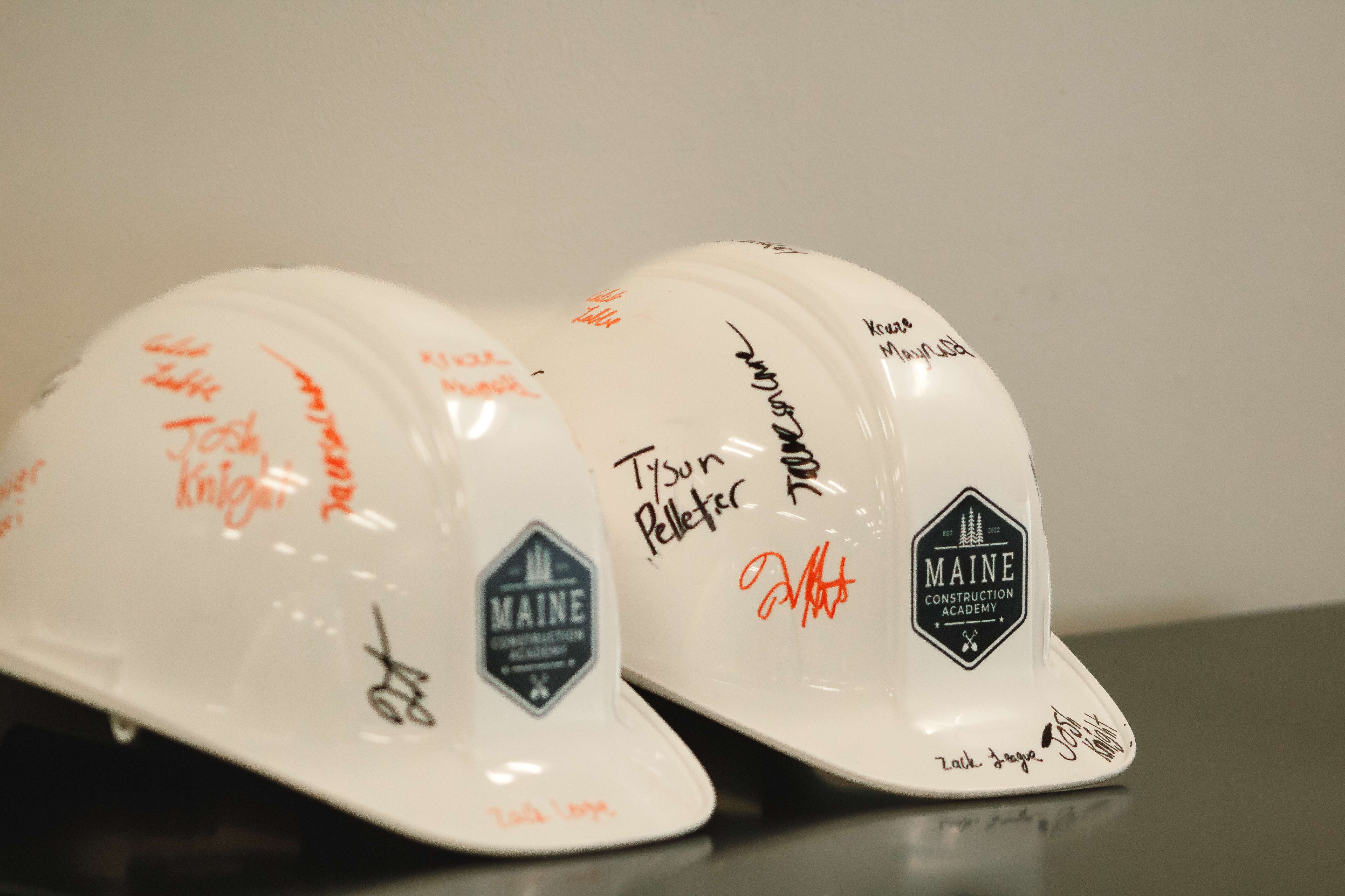 2 white hardhats with writing