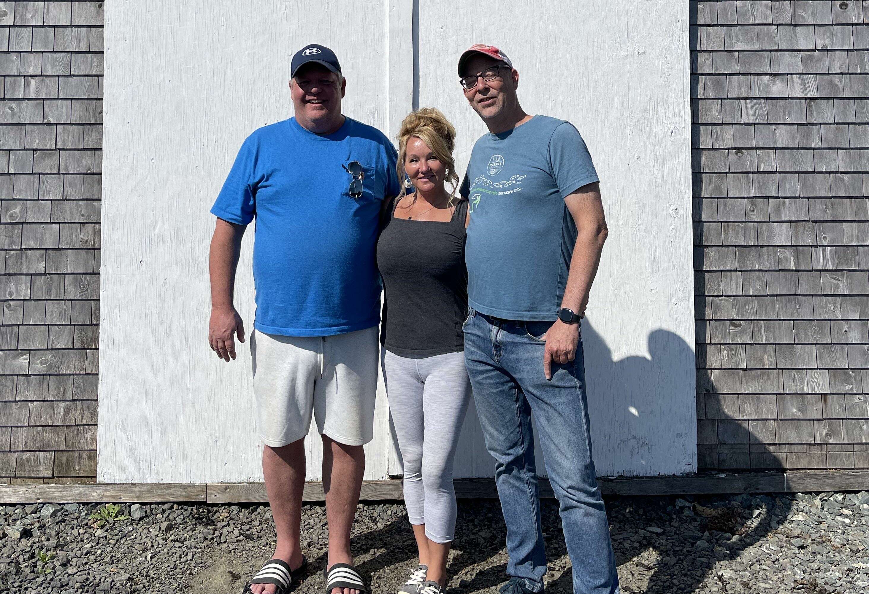 3 people in a row in front of shed