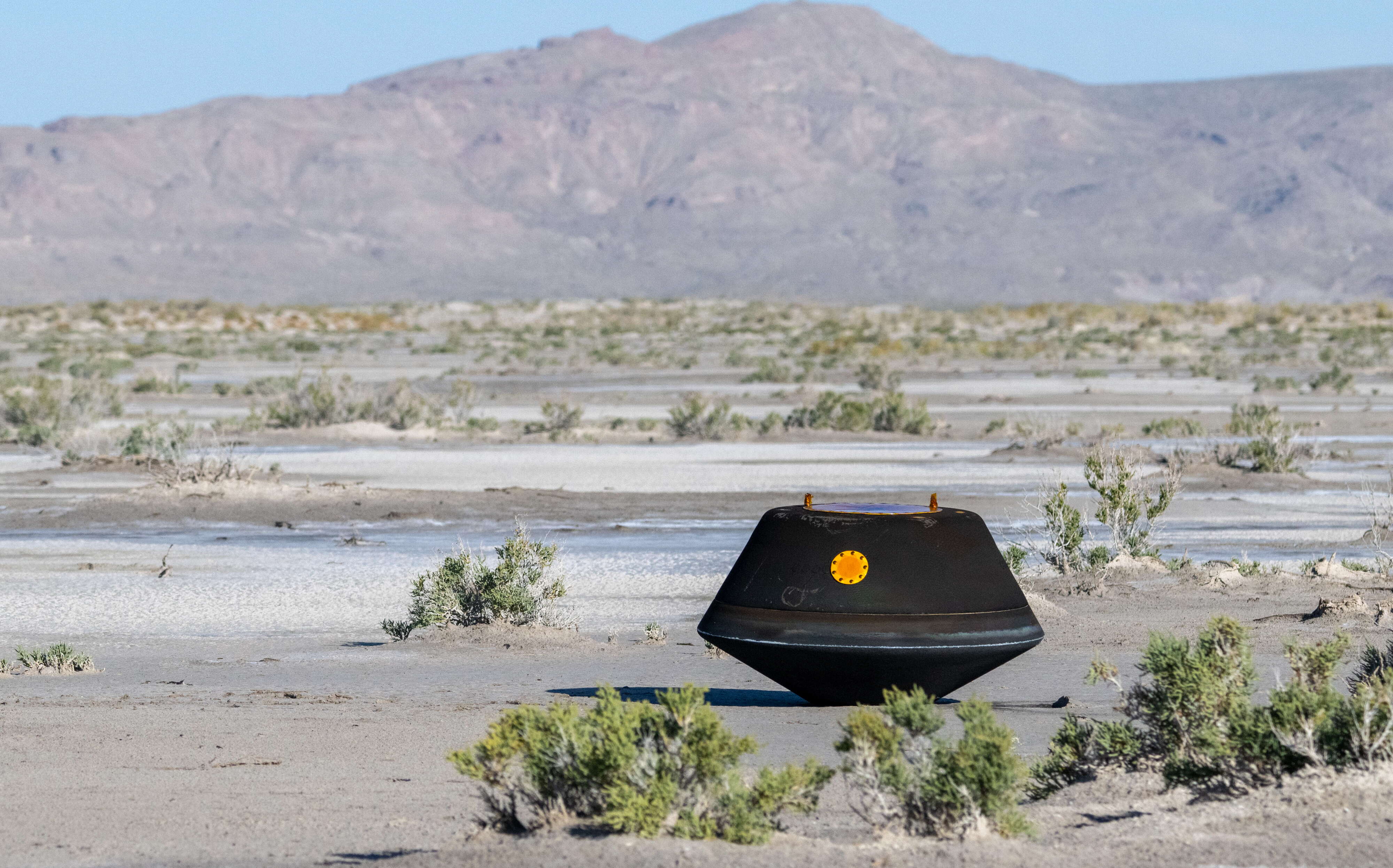 space capsule in desert with scrub around it