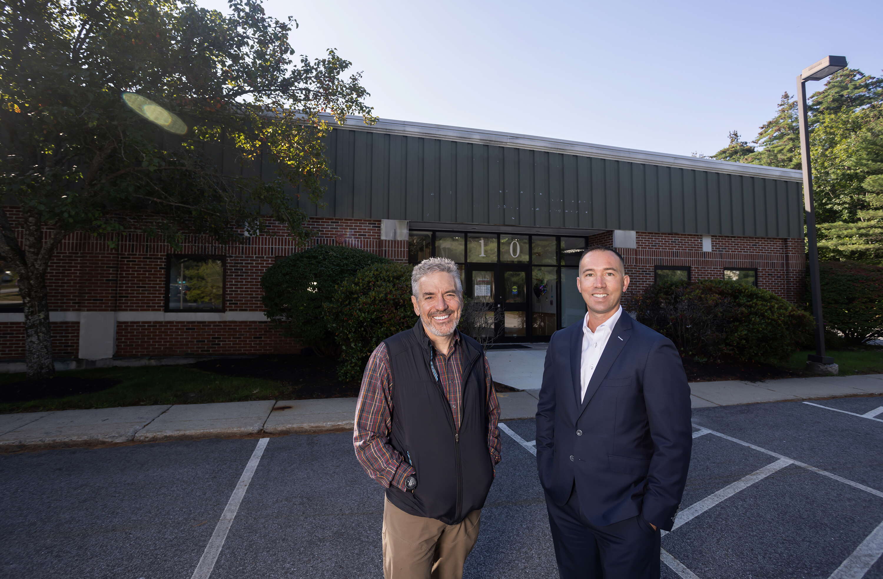 2 people standing in parking lot in front of building