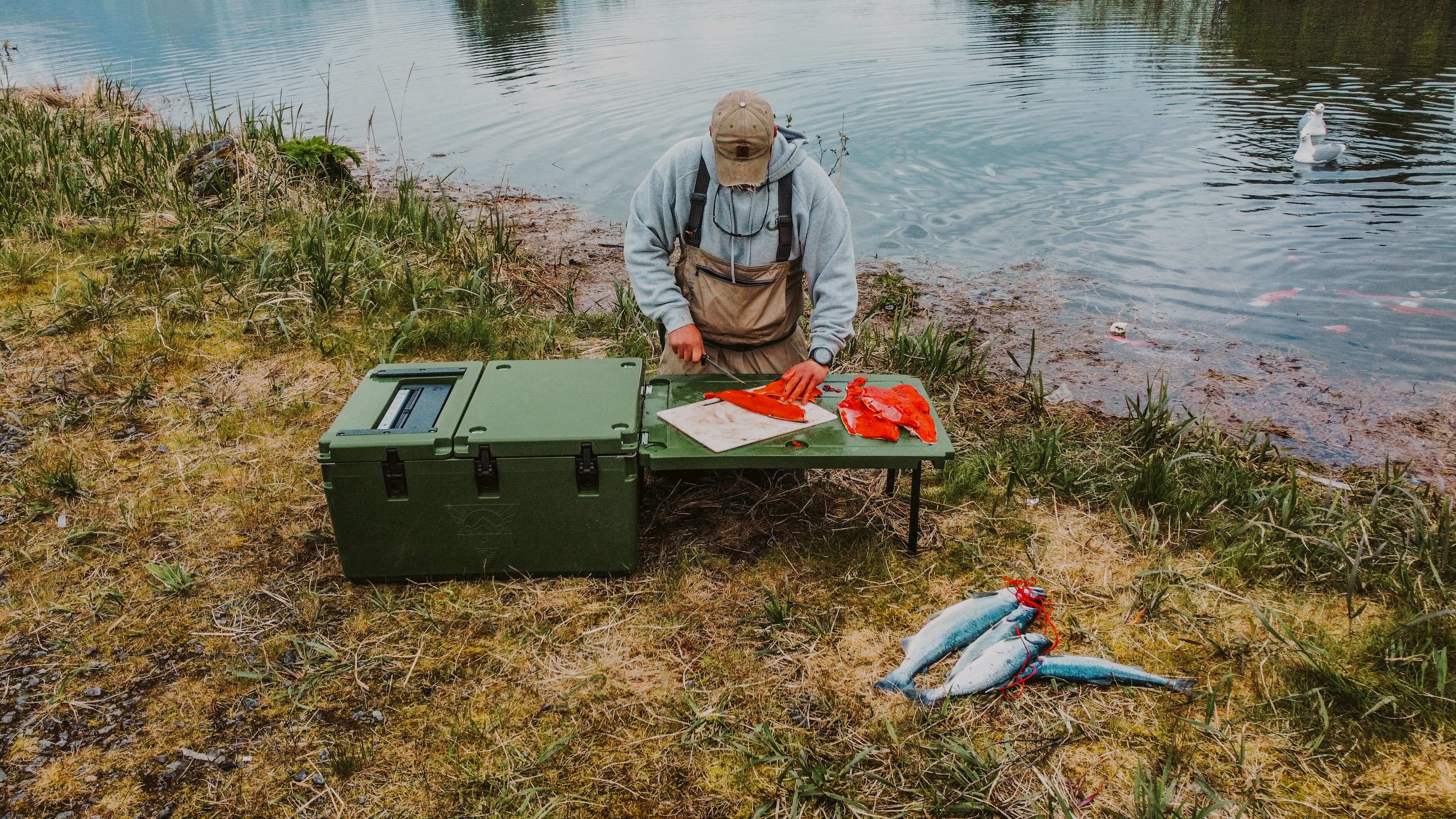 person slicing fish near river