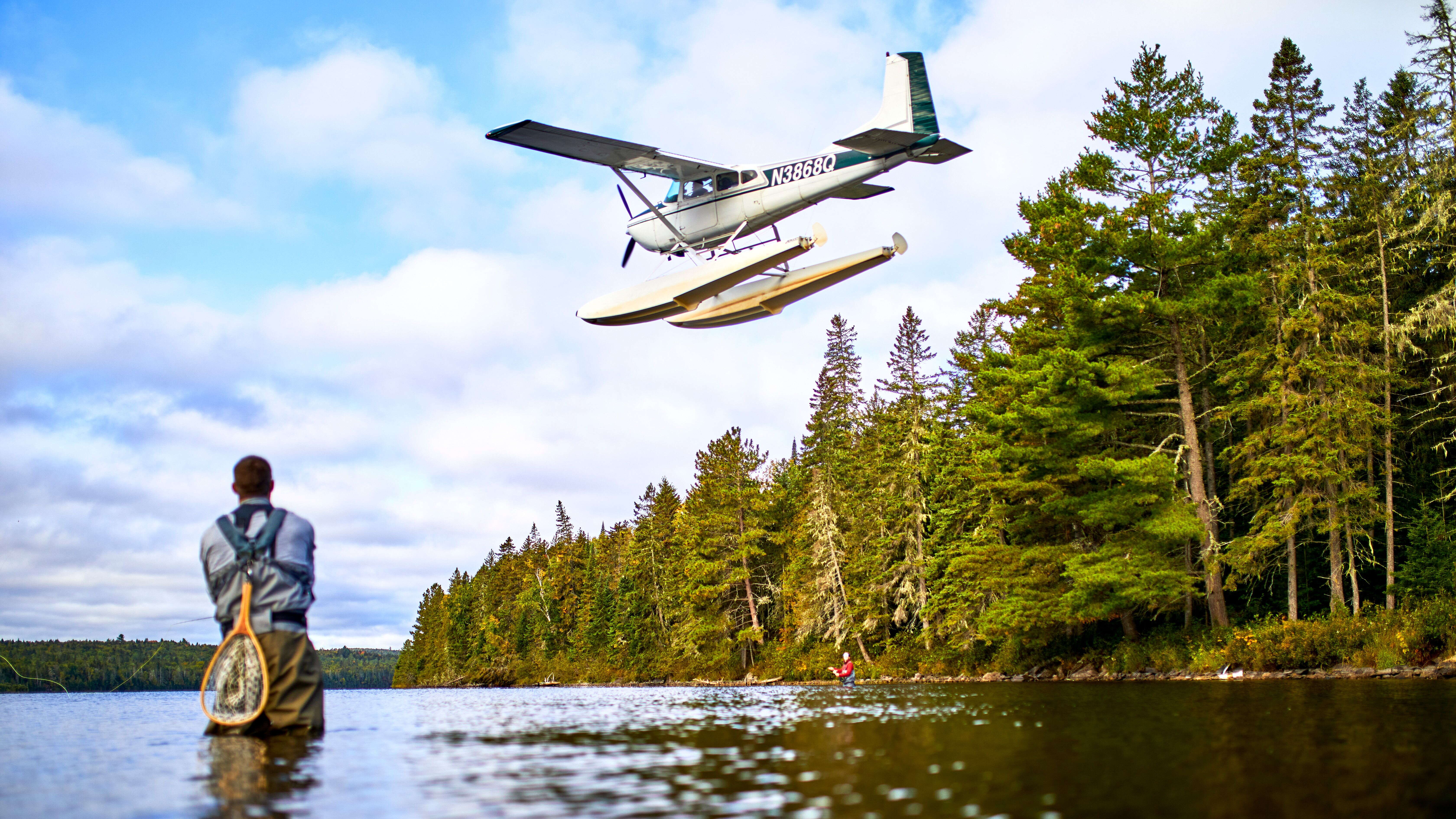 Fisherman in water, plane above 