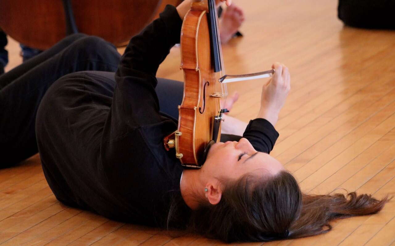 person lying on floor playing violin