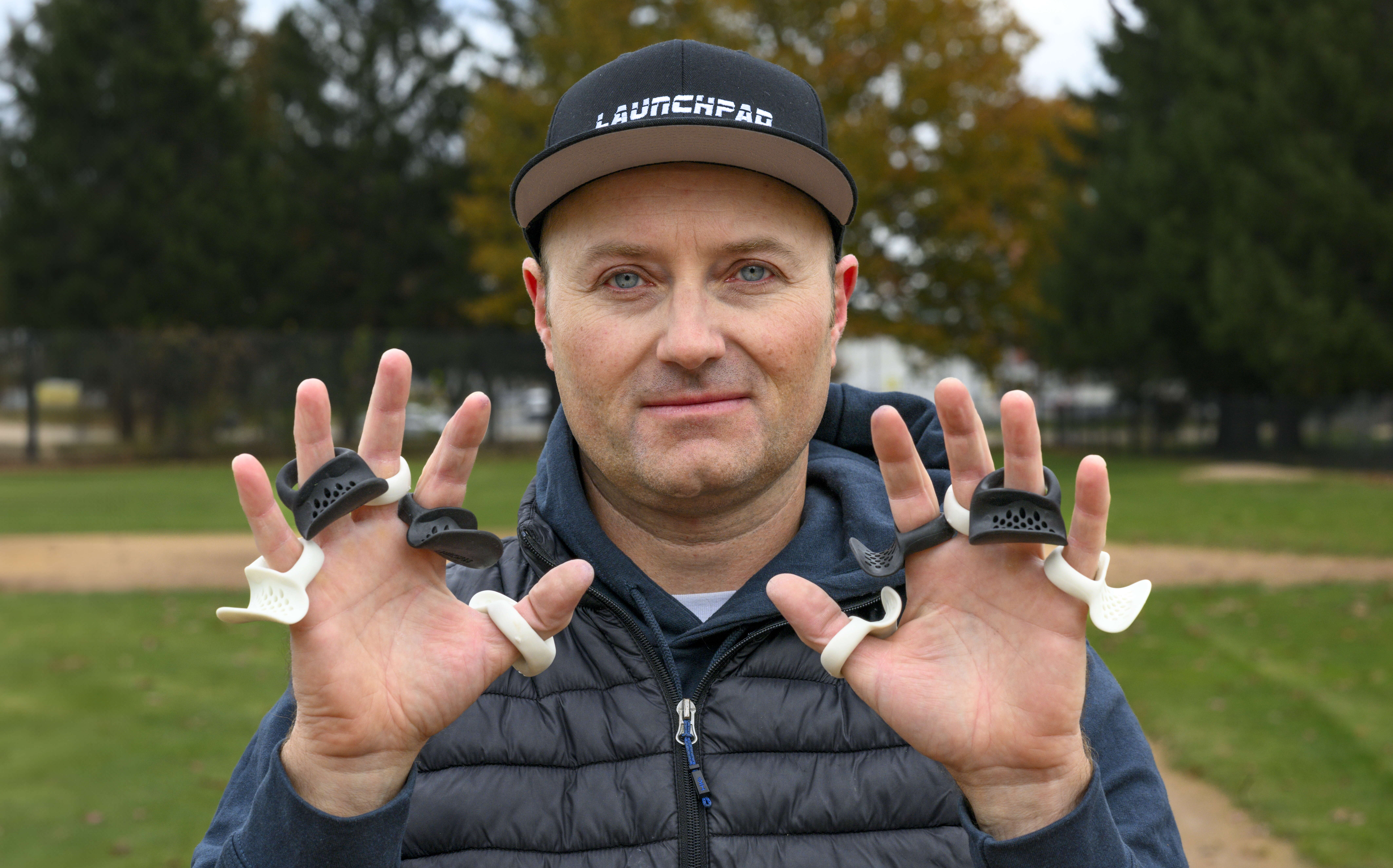 Man holding up two hands with protective thumb guards on each finger, displayed like rings.