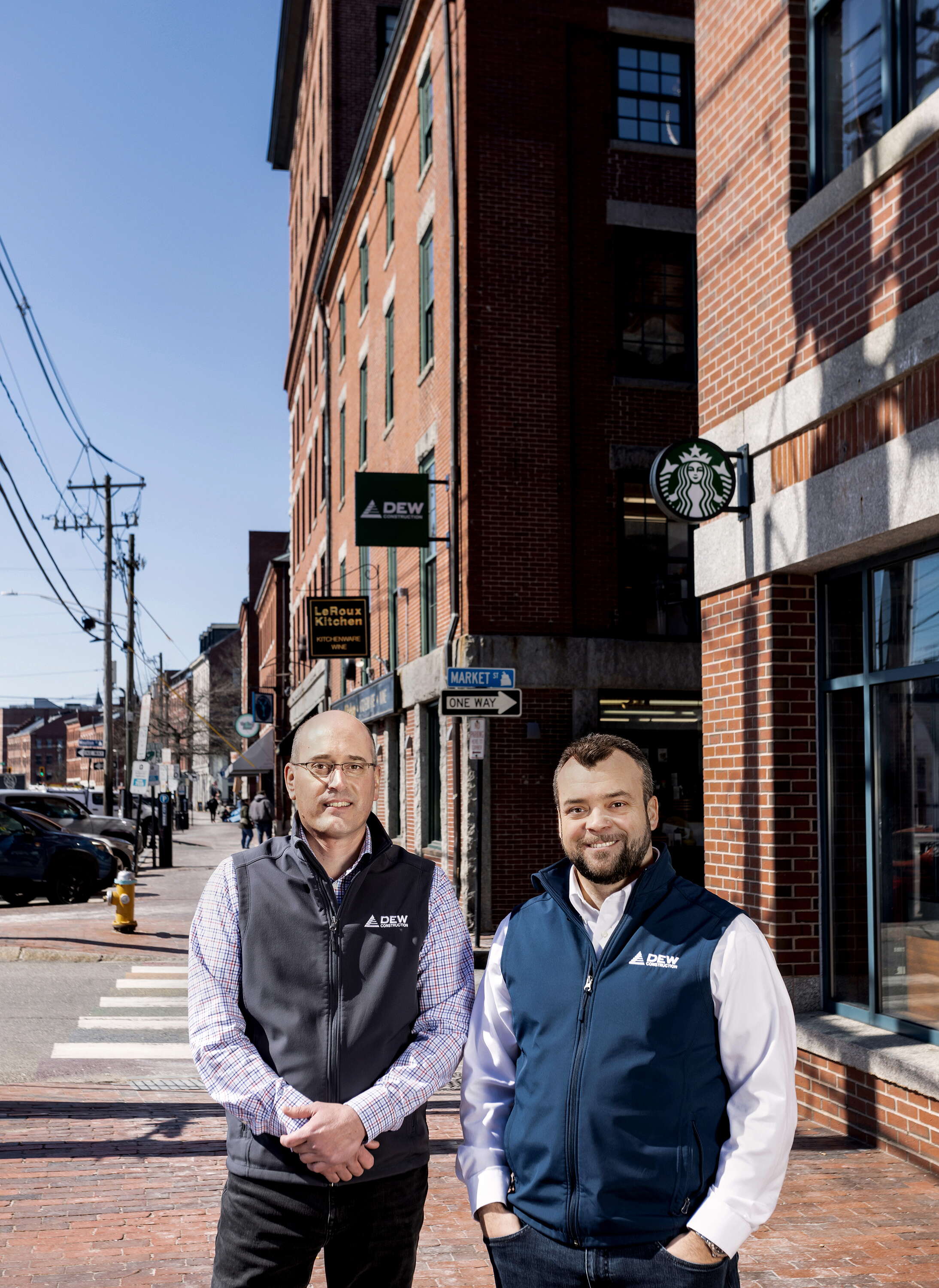 two people on brick sidewalk outside brick buildings