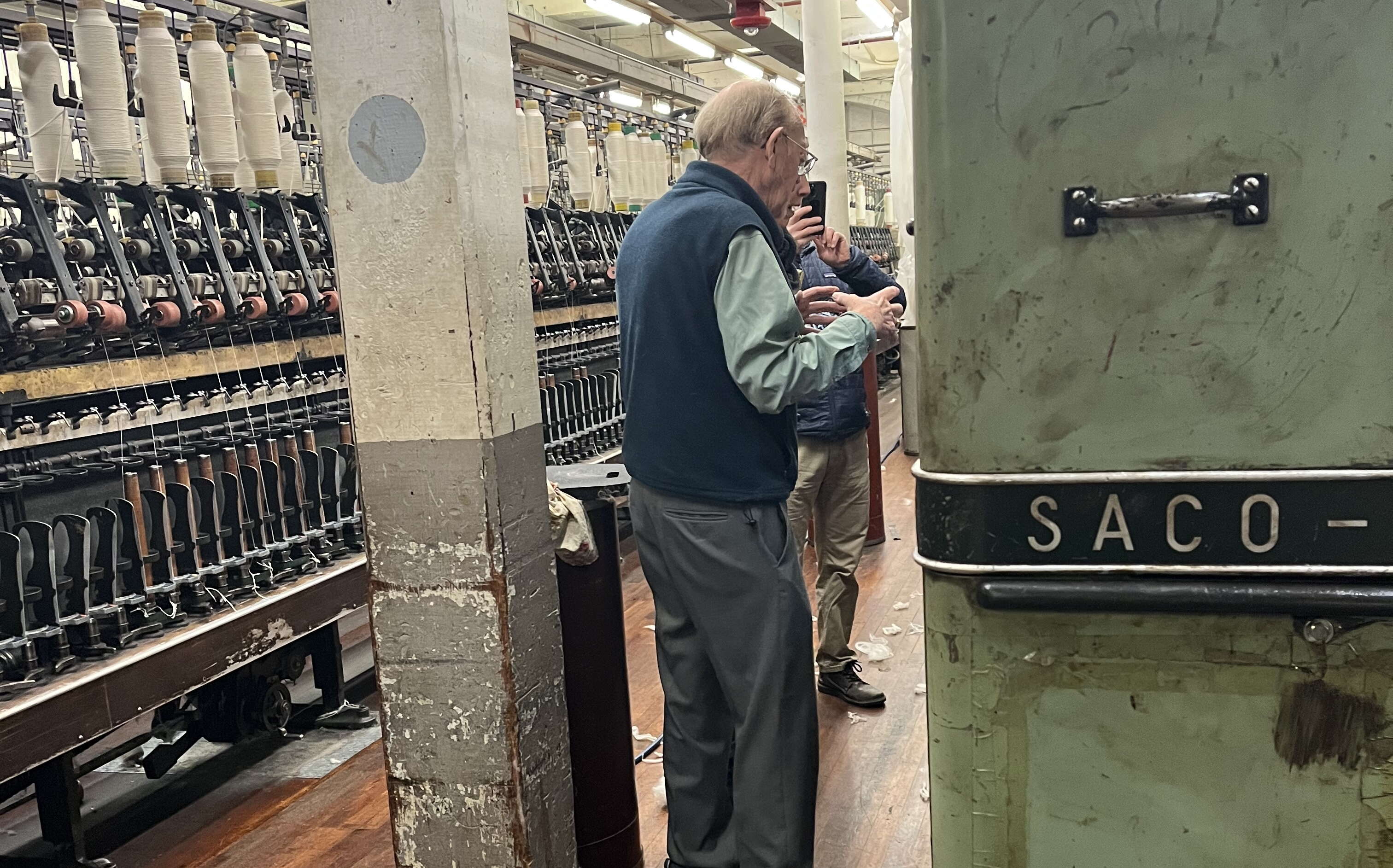 2 people talk next to some machinery.