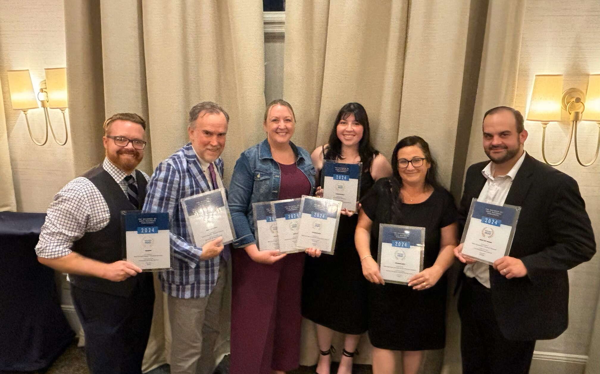 New England Business Media staff members holding awards from the Alliance of Area Business Publishers.