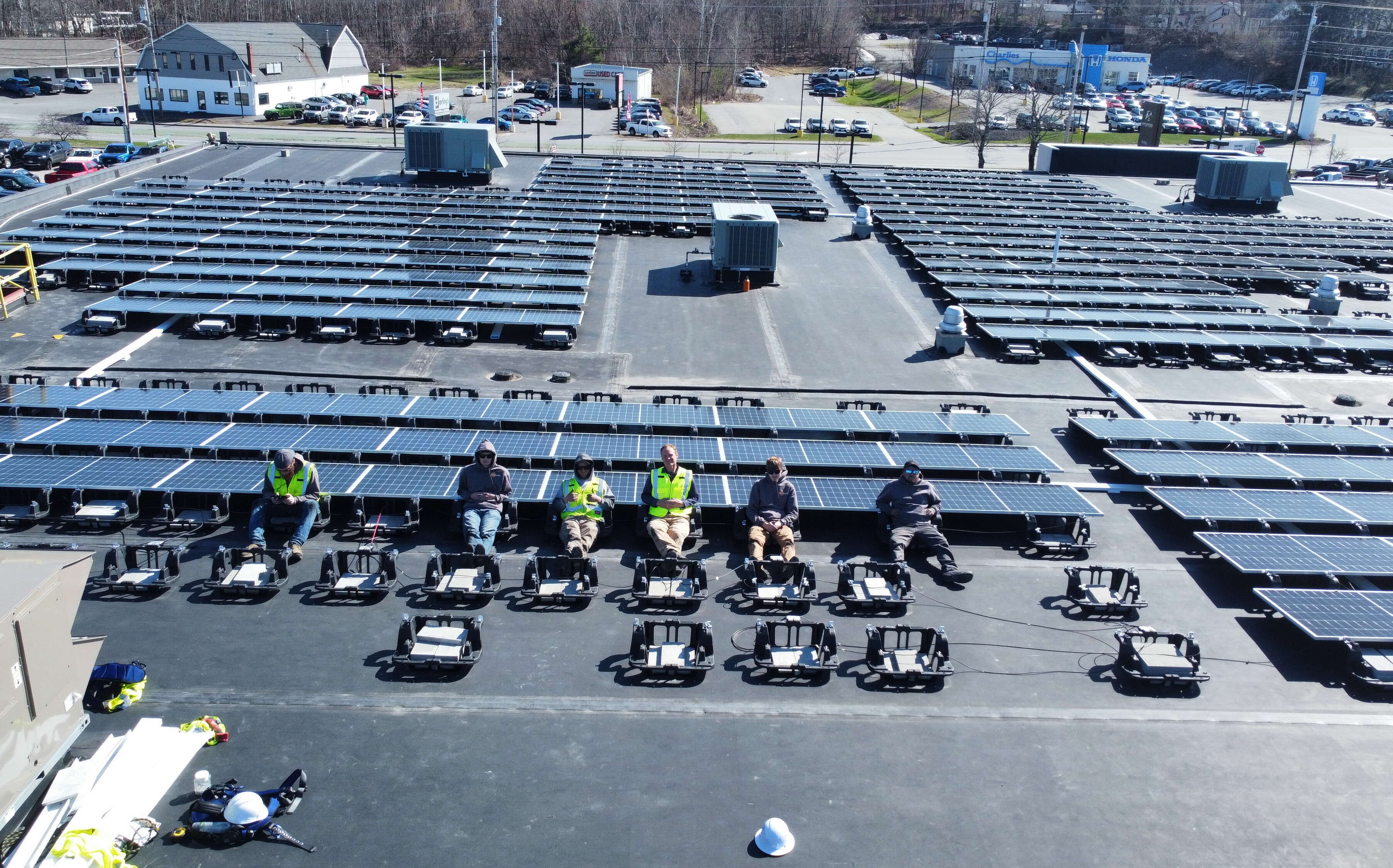Workers with SolarLogix sit on a roof surrounded by solar panels and equipment.
