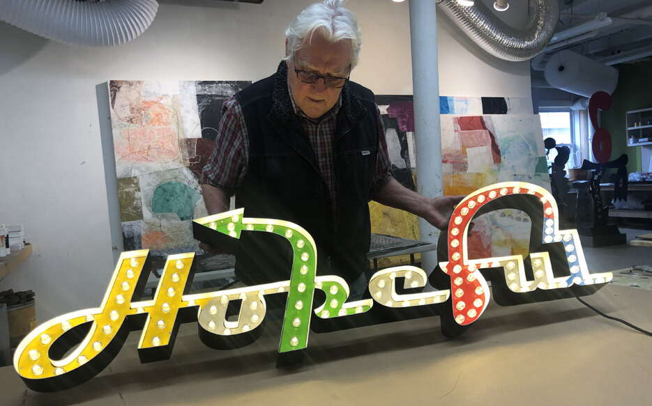 Charlie Hewitt holds one of his neon signs.