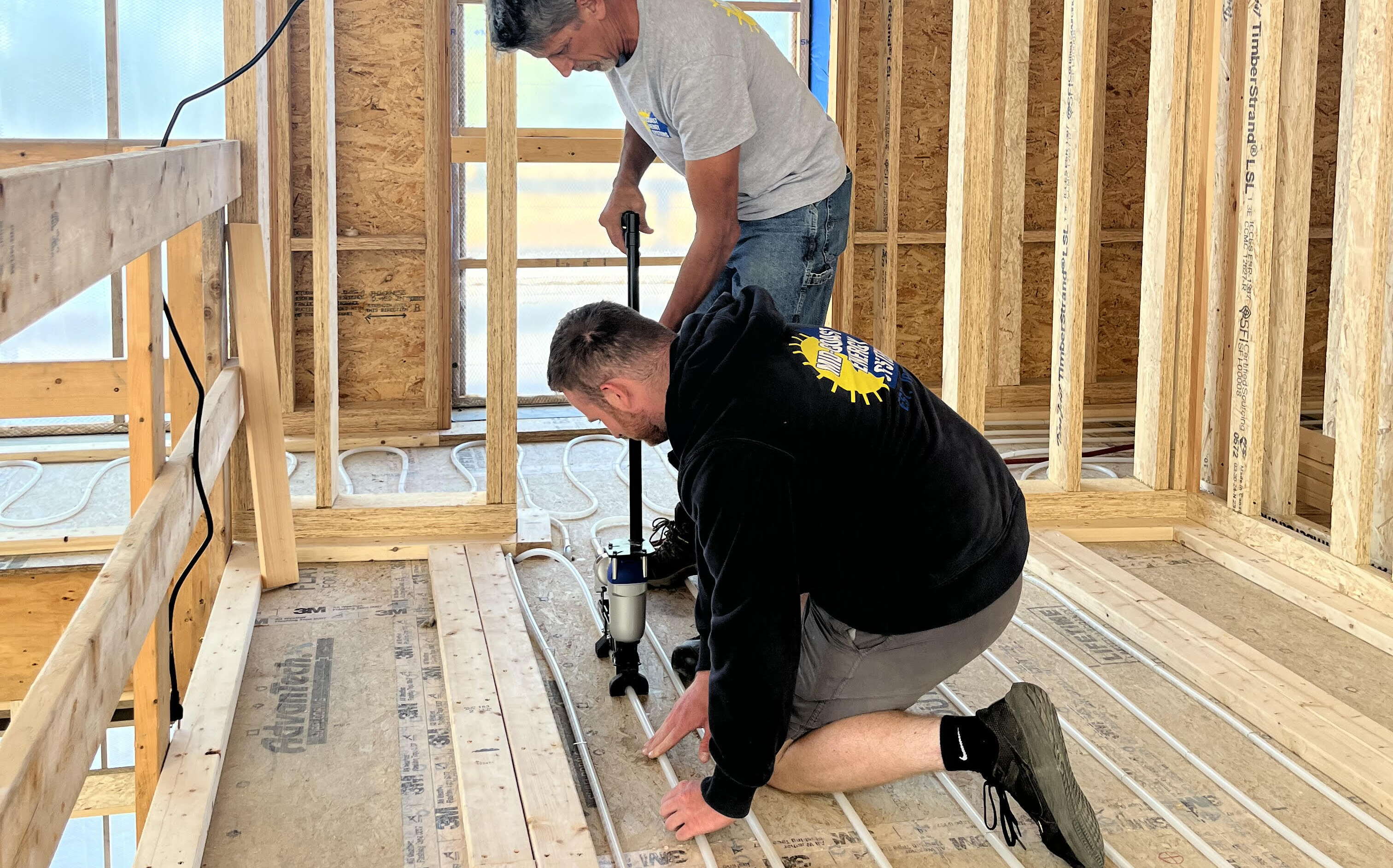 Two people install wires in a new construction building.