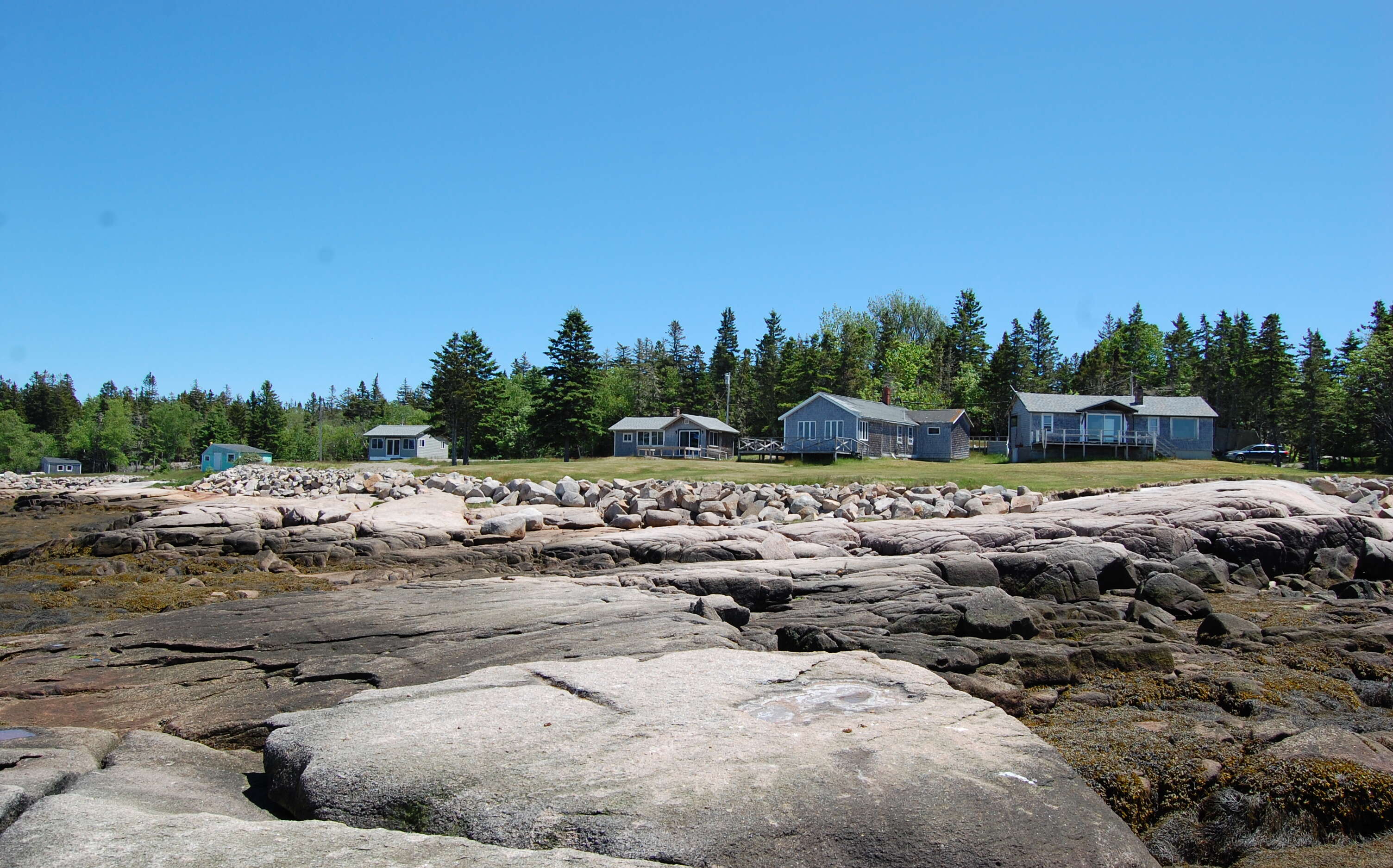 Cottages are seen above a rocky shorline.
