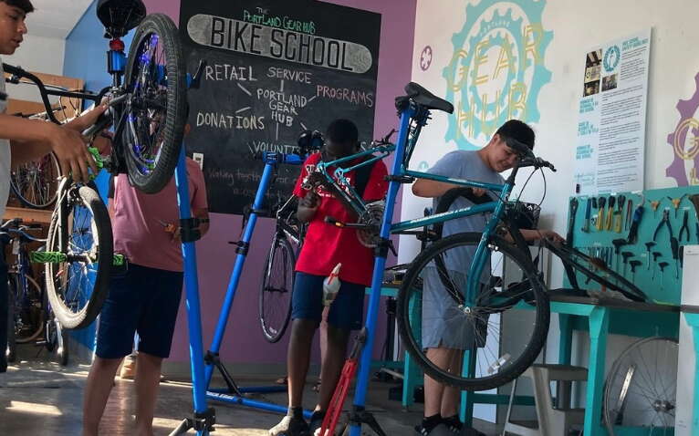 People work on bikes that are on stands.