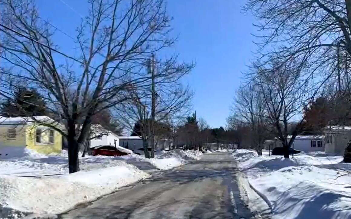 A road has homes and snowy lawns.