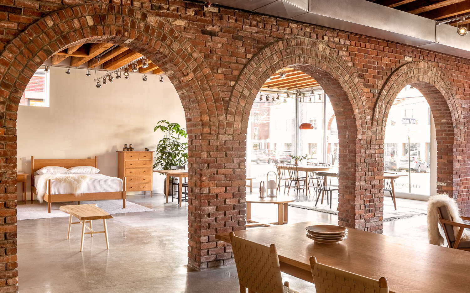 A store interior has furniture, brick arches and big windows.