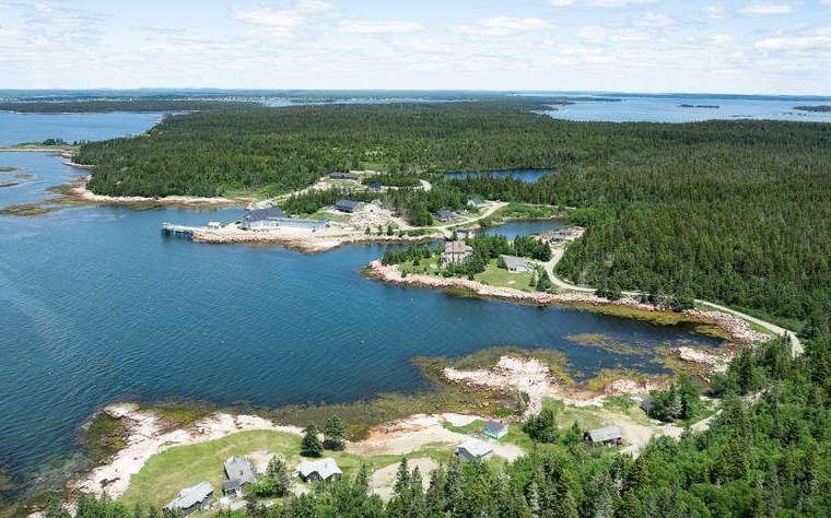 An aerial view of woods, water and buildings.