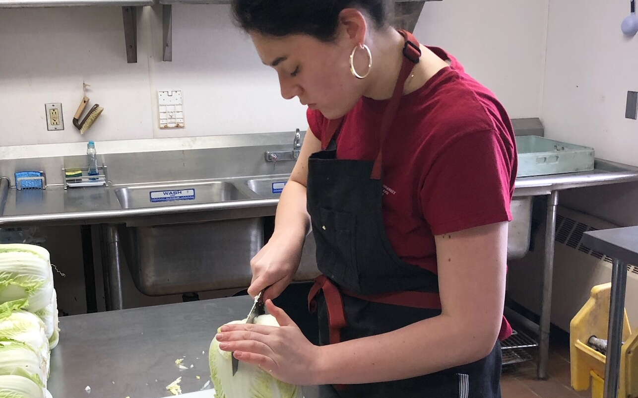 A person chops cabbage in a kitchen.