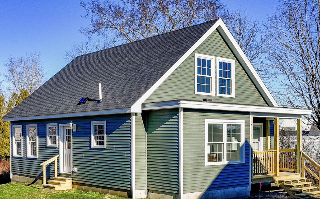 An exterior view of a new house with green siding.