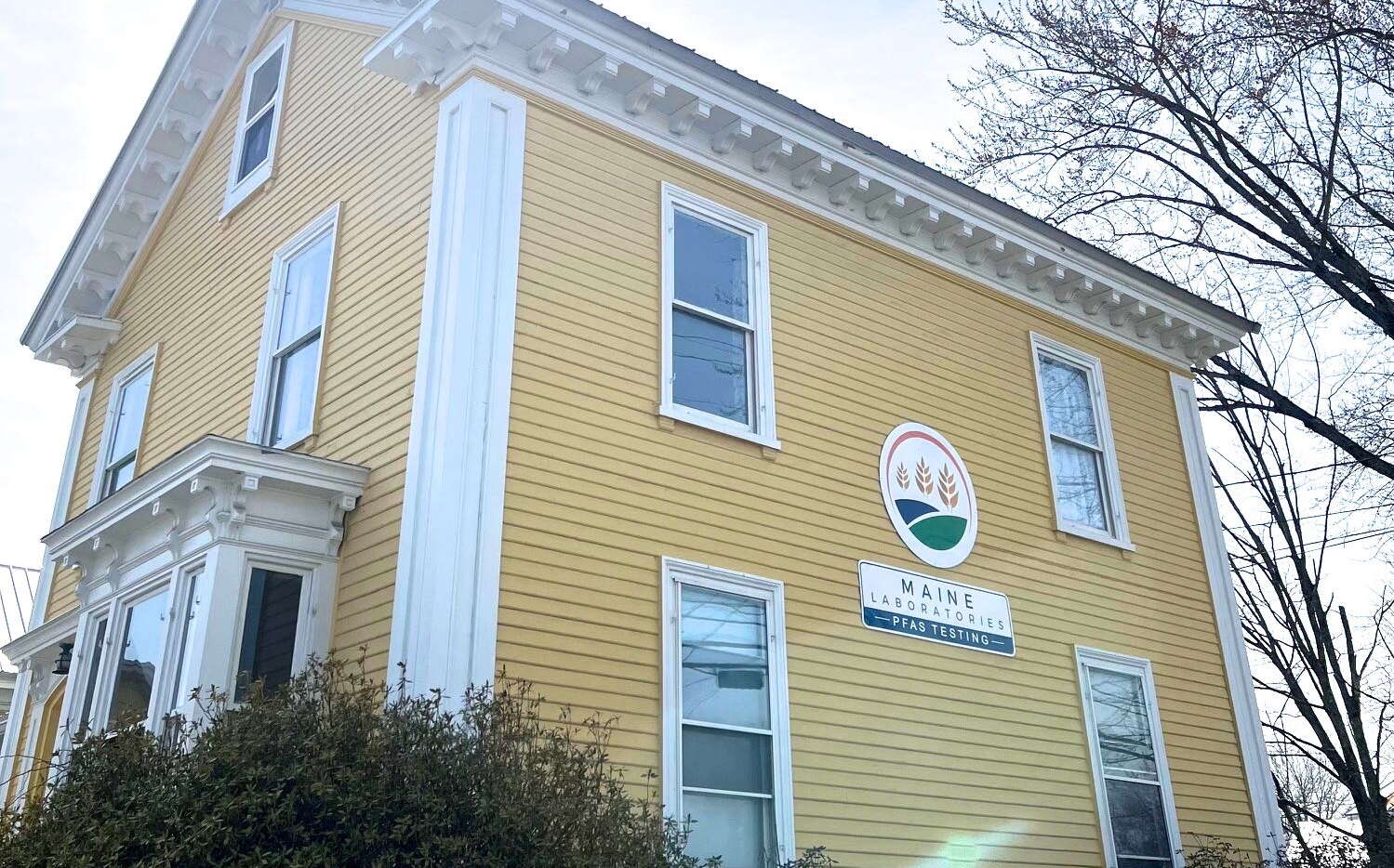A building has yellow siding and a sign.